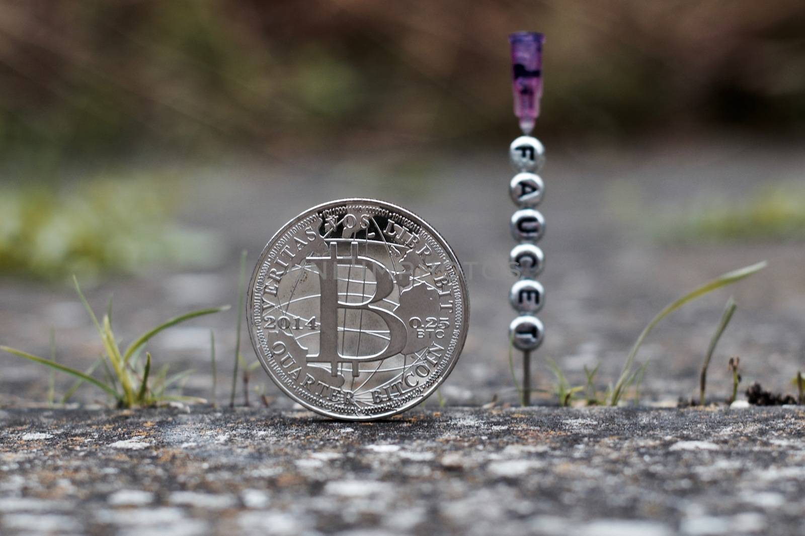 Digital currency physical silver bitcoin coin near faucet inscription on the needle.