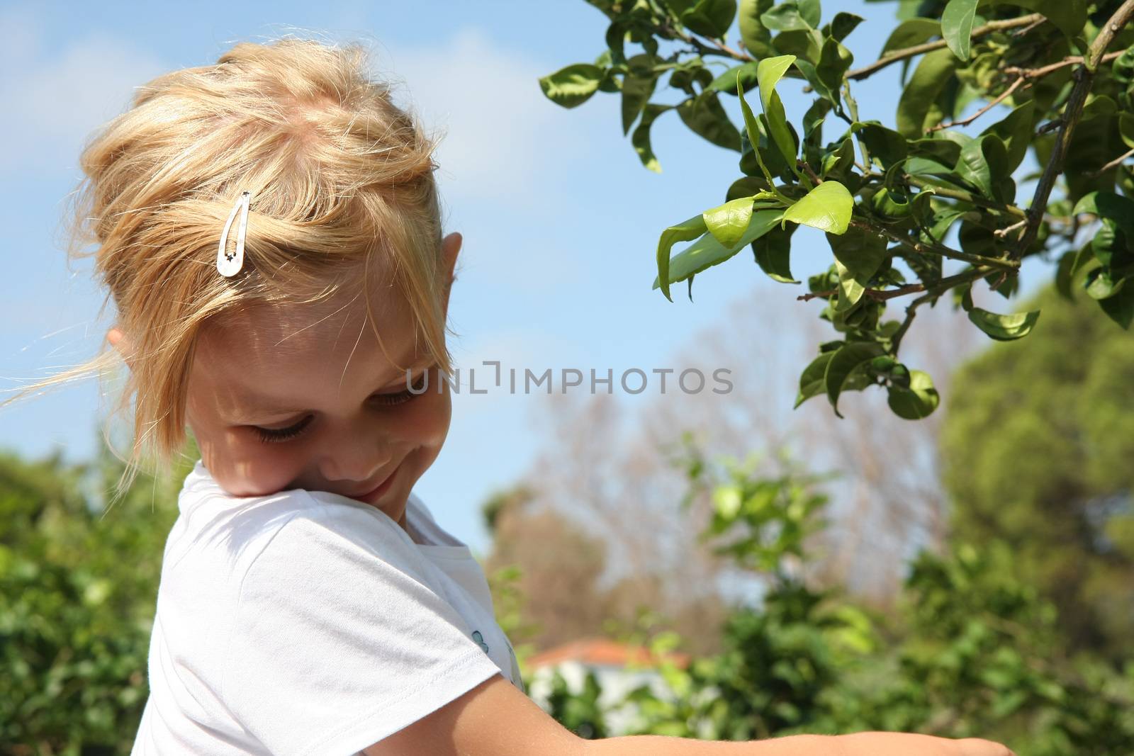 Portrait of cute baby girl posing near leafage