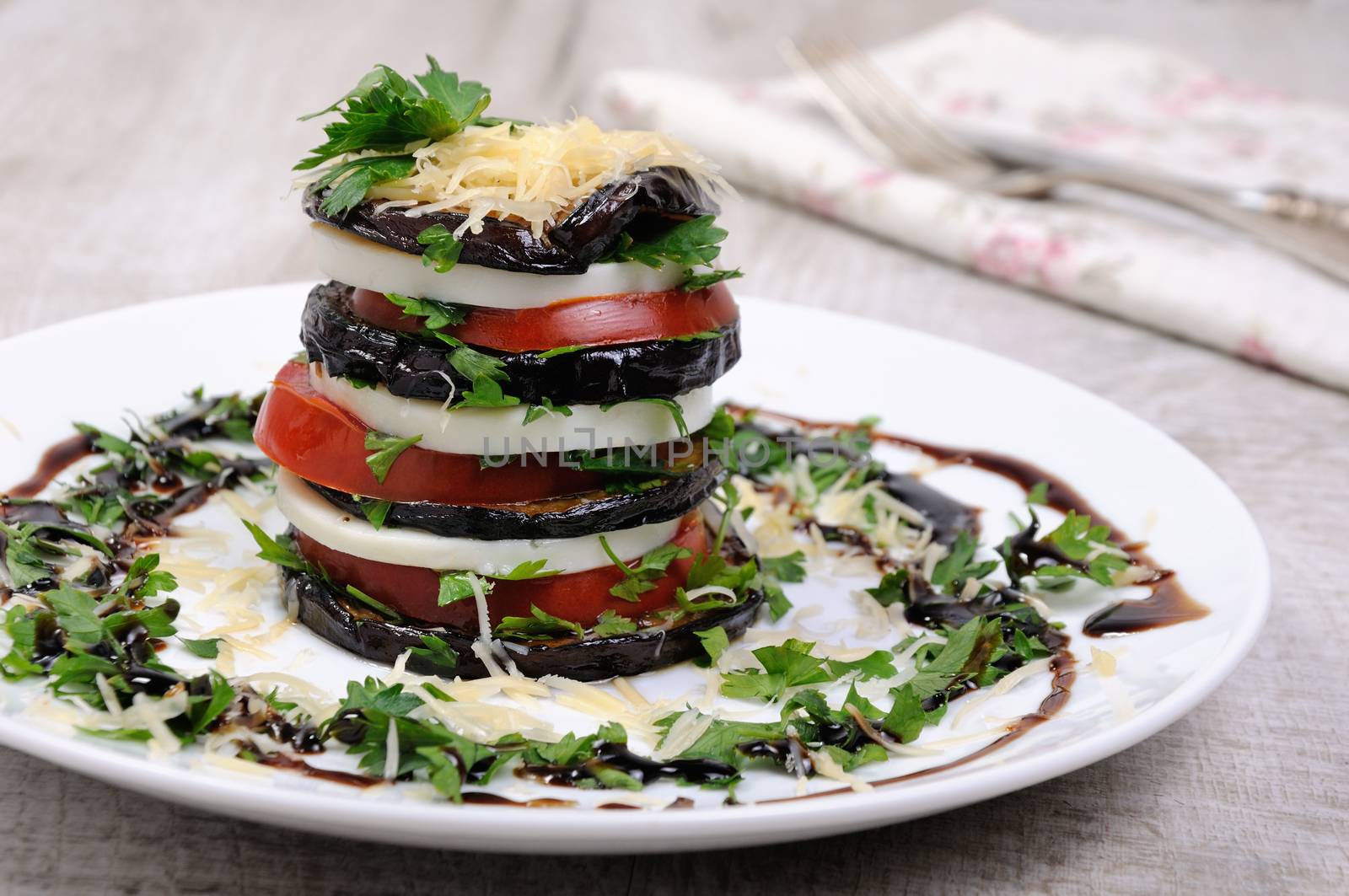 Appetizer from eggplant , slices of mozzarella combined in a pile with tomatoes spilled with herbs, seasoned   Parmesan cheese
