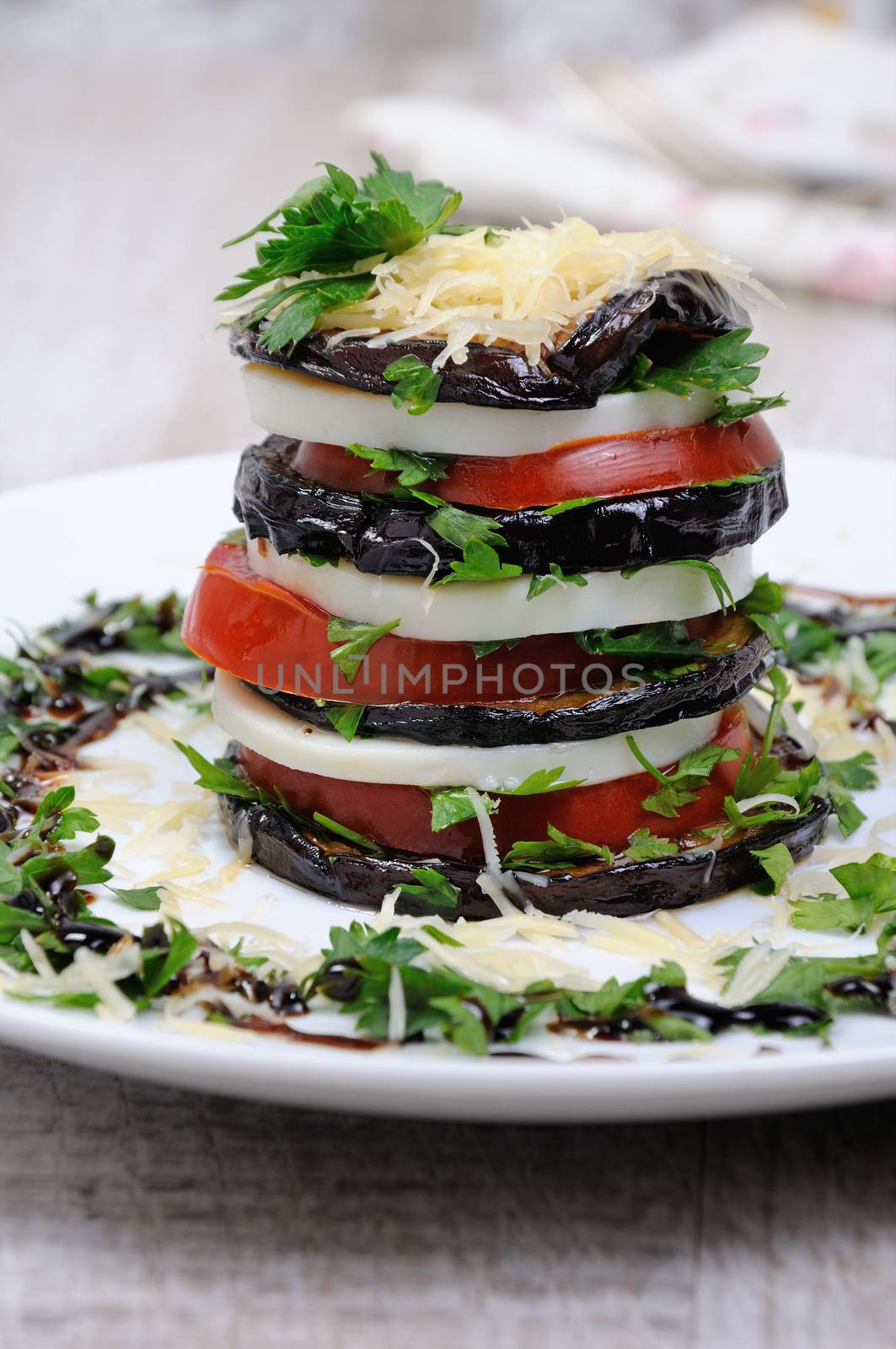 Appetizer from eggplant , slices of mozzarella combined in a pile with tomatoes spilled with herbs, seasoned   Parmesan cheese