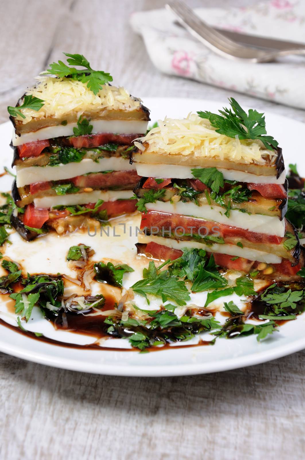 Appetizer from eggplant , slices of mozzarella combined in a pile with tomatoes spilled with herbs, seasoned   Parmesan cheese. In section