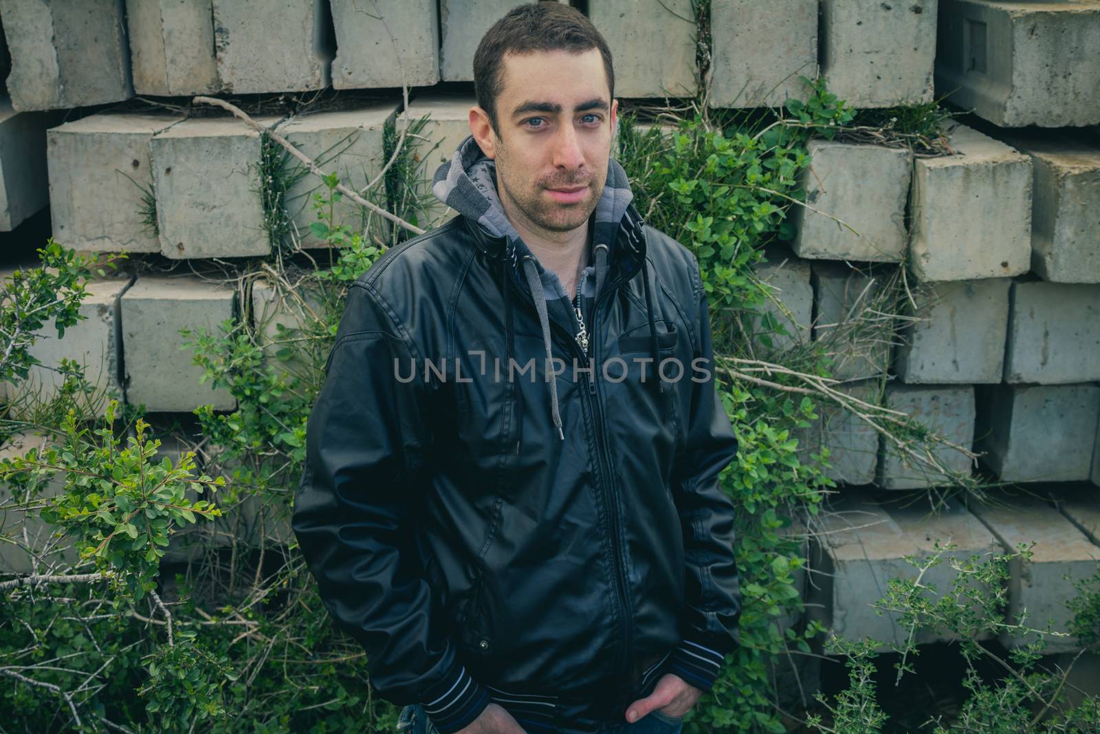 Man with serious face posing outdoor in abandoned industrial place.