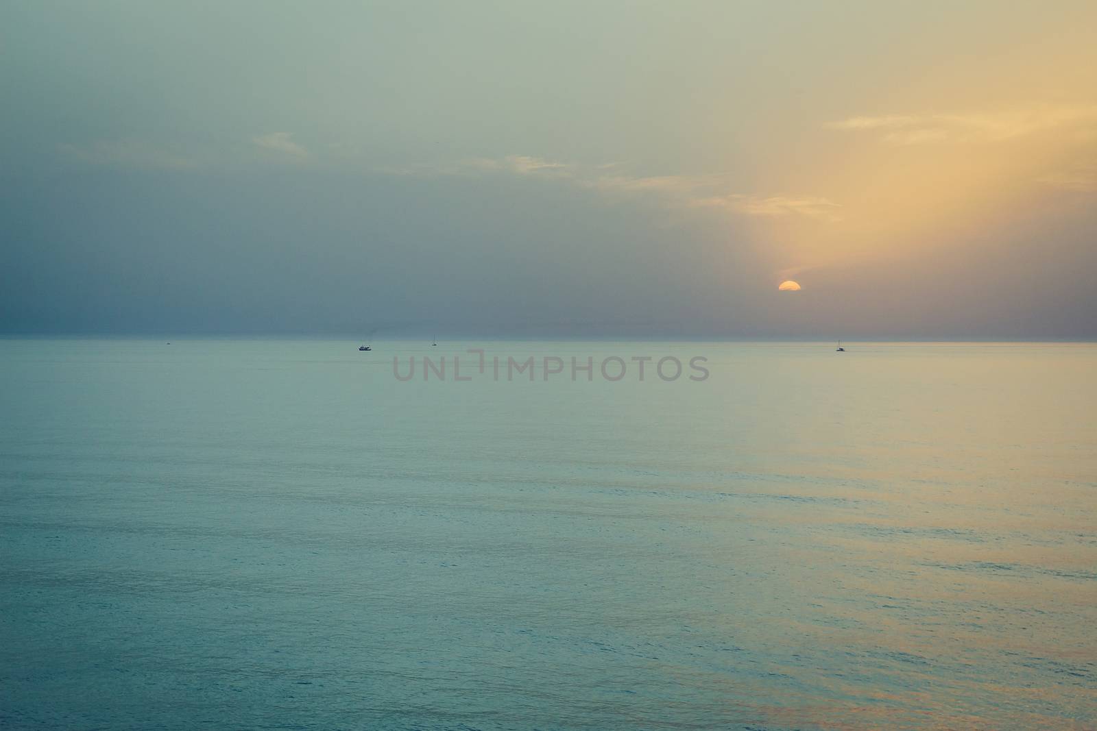 Sunset over the sea. Silhouette of boats on the horizon.