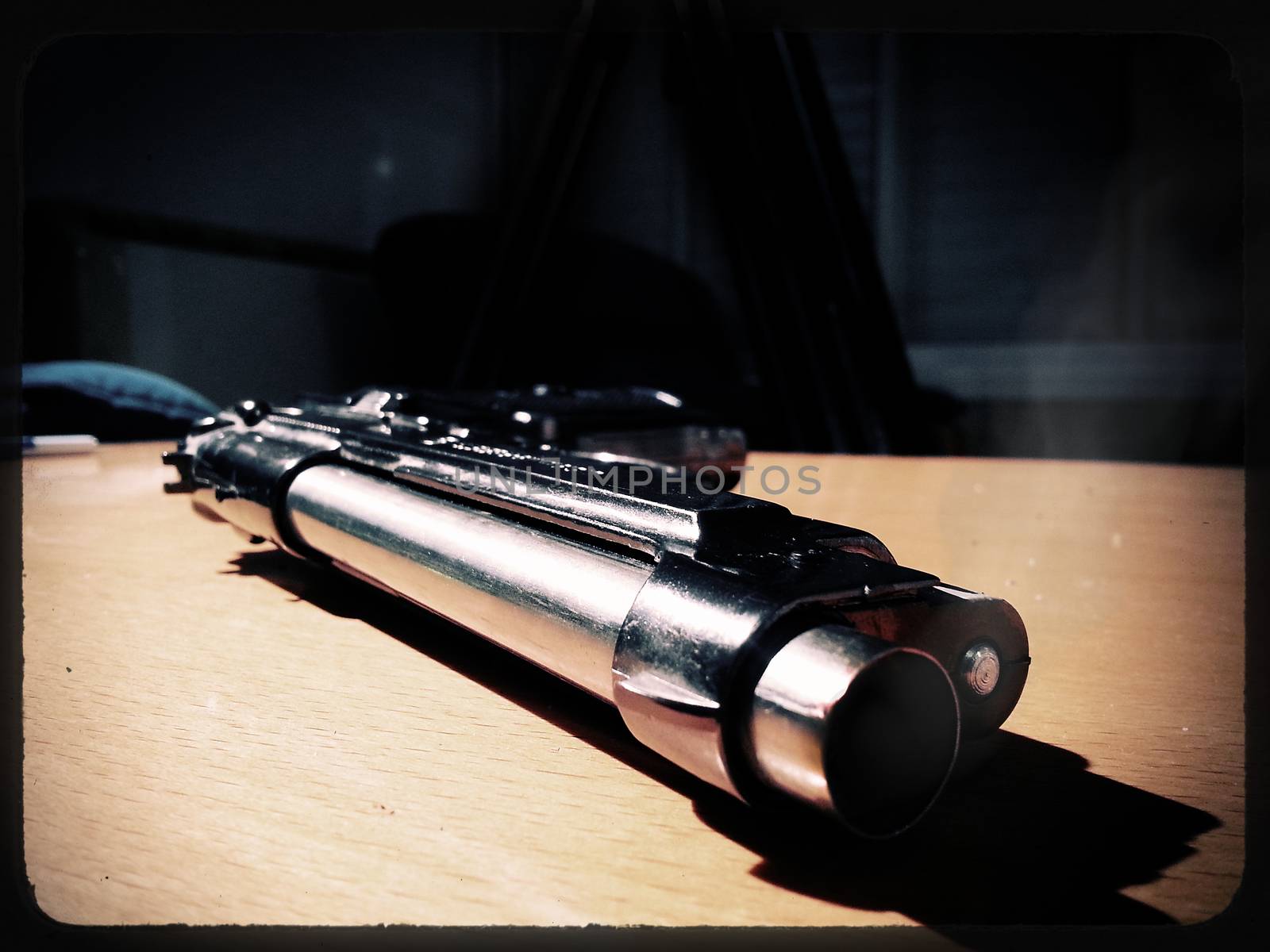 Silver 9mm pistol lying on a wooden table.
Smoke coming from the barrel of the gun.