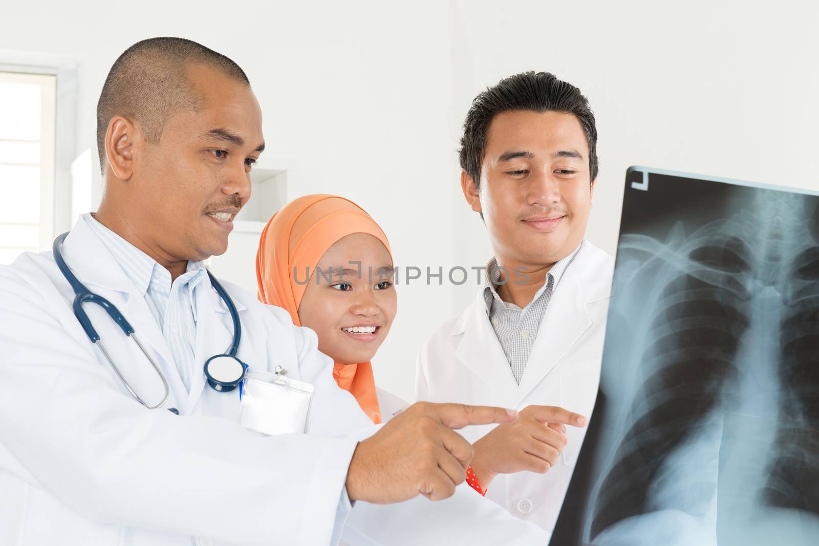 Group of doctors analyzing x-ray together in medical office. Southeast Asian Muslim people.