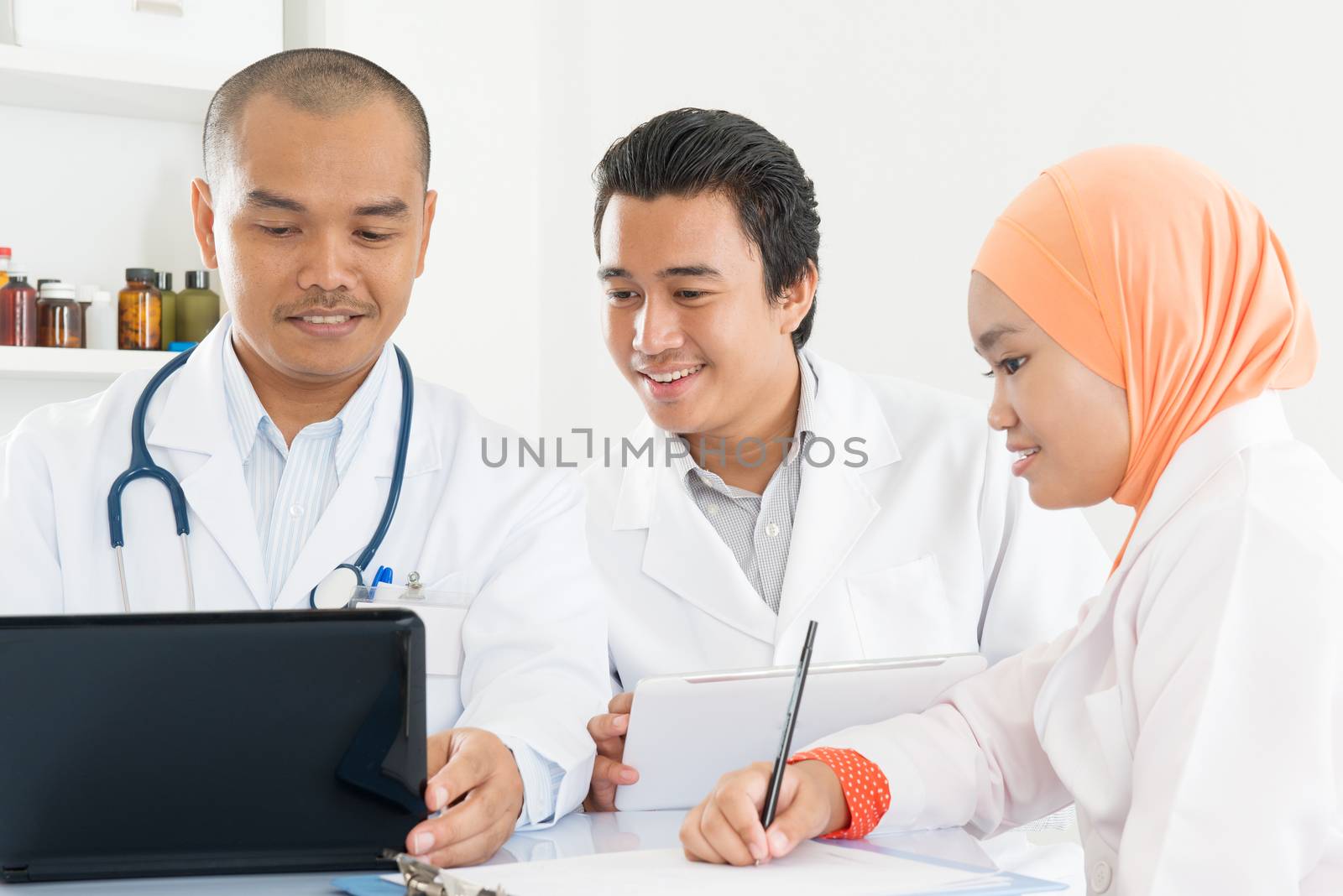 Doctor and nurses looking at laptop computer in the hospital. Southeast Asian Muslim medical people.