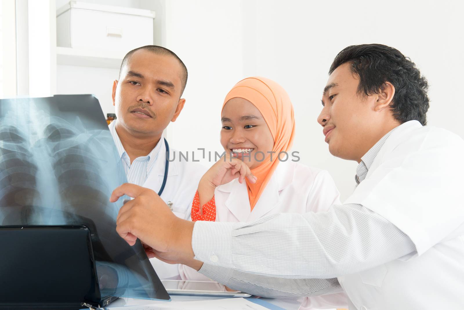 Happy medical team discussing and looking at xray scan. Southeast Asian Muslim doctors and nurses.