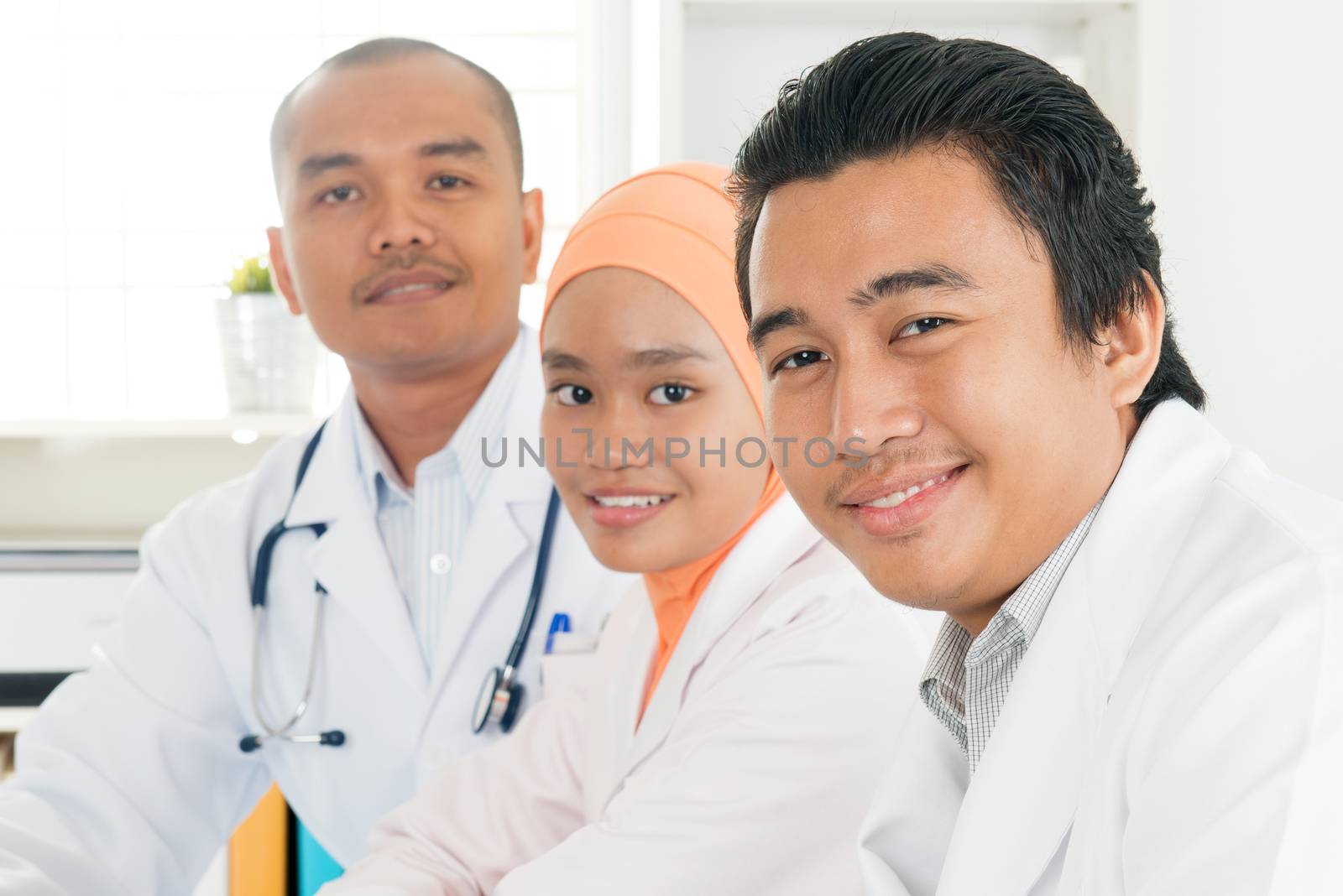 Portrait of medical team sitting in hospital office, Southeast Asian Muslim doctors and nurses.