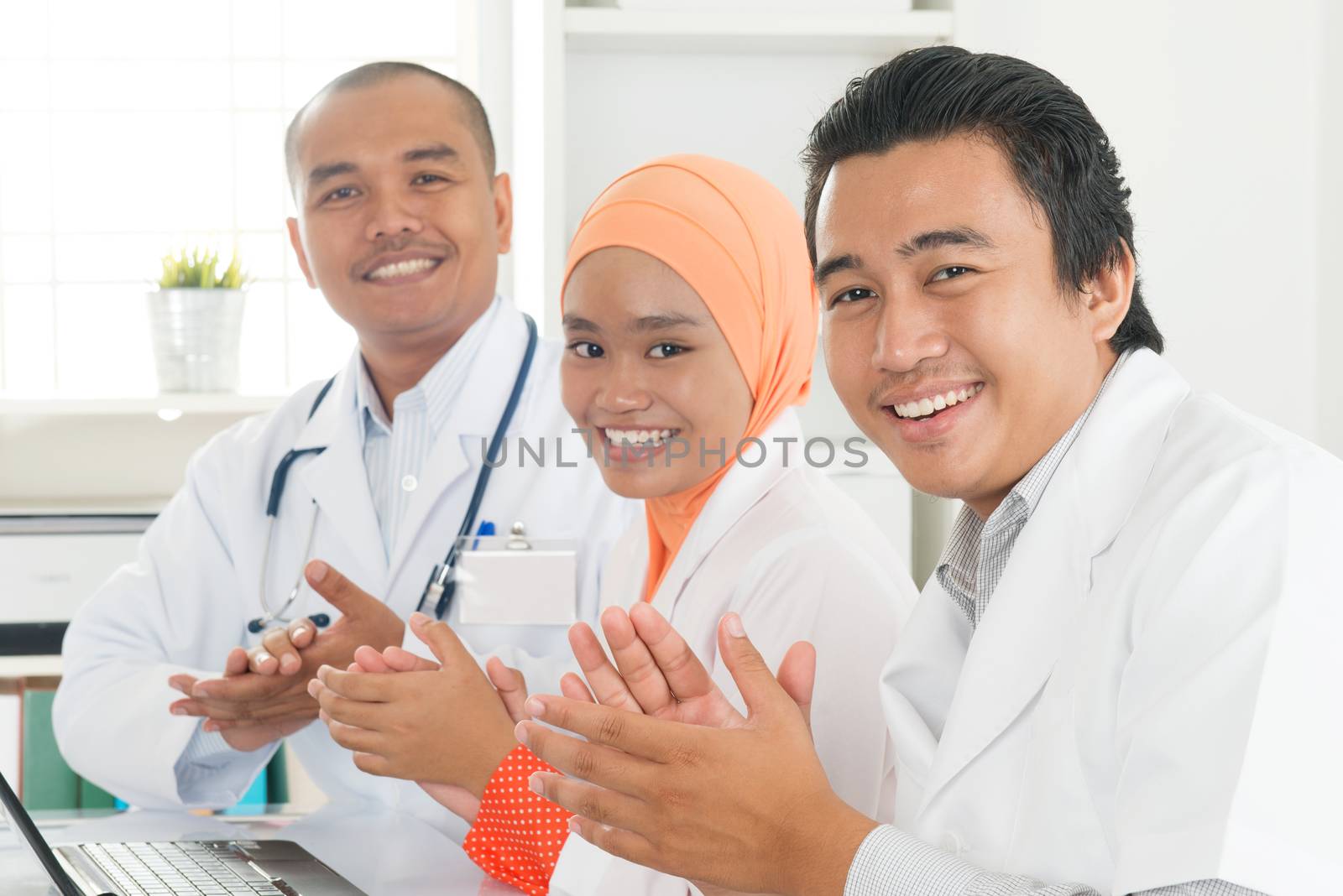 Medical team clapping their hands during a meeting, Southeast Asian Muslim doctors and nurses.