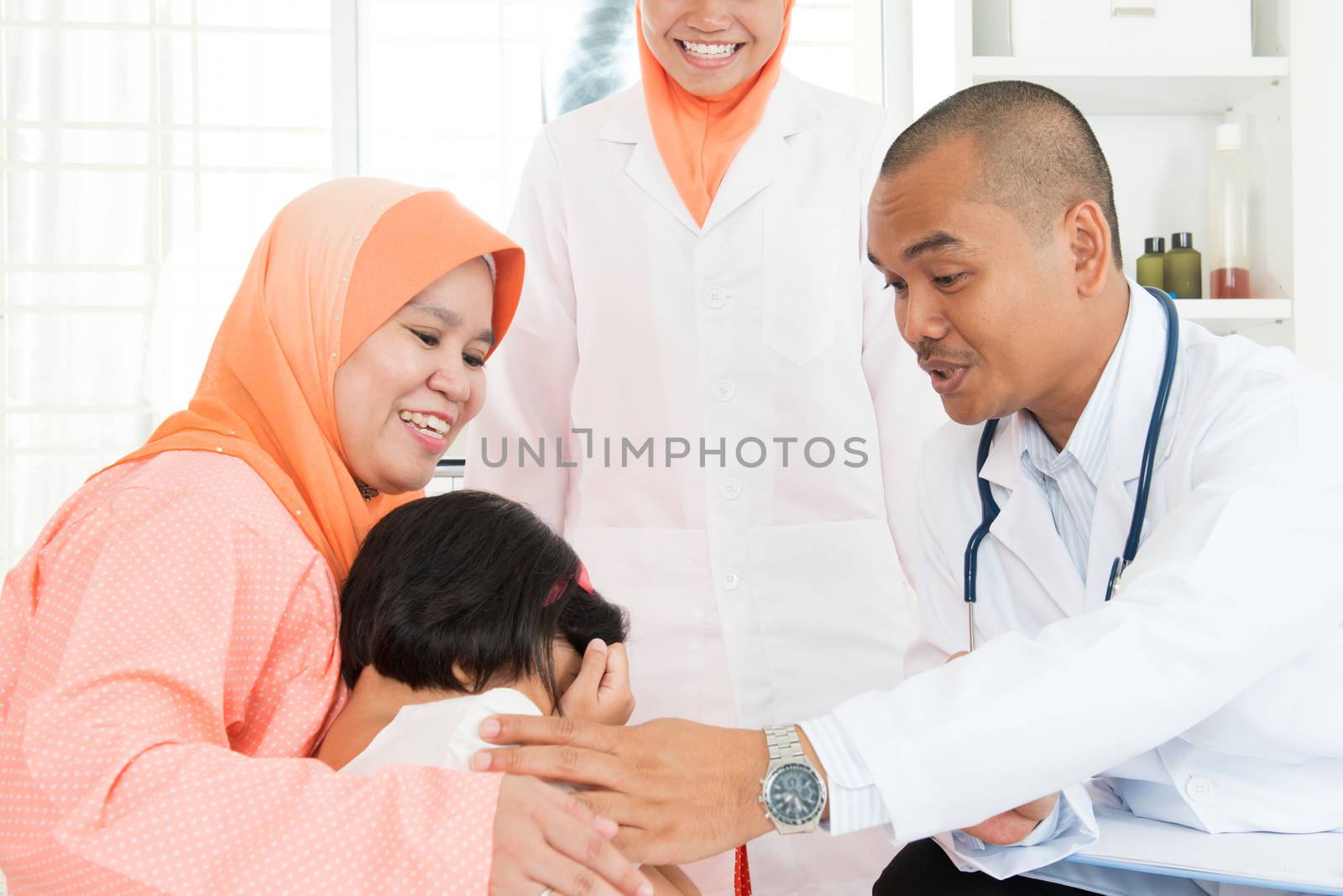 Children scare of doctor at hospital.  Southeast Asian Muslim family.