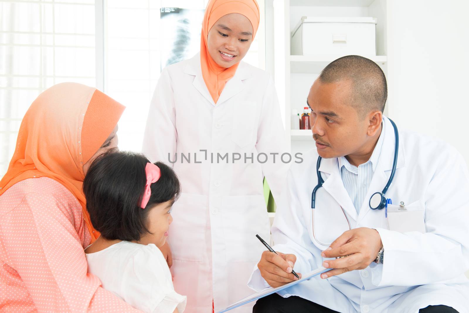 Southeast Asian pediatrician and little girl at hospital. Muslim family.