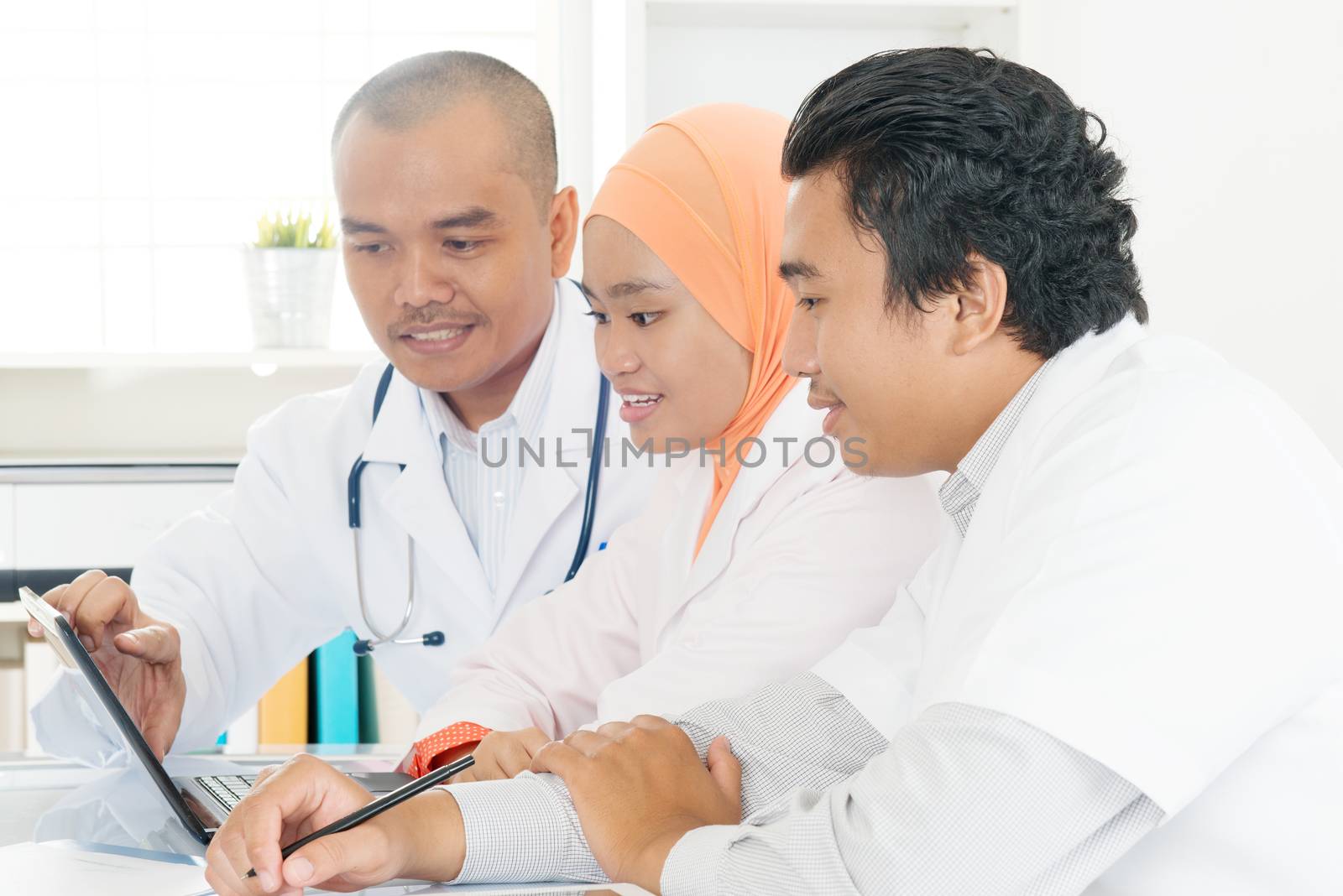 Doctors working together in the office. Southeast Asian Muslim medical people.