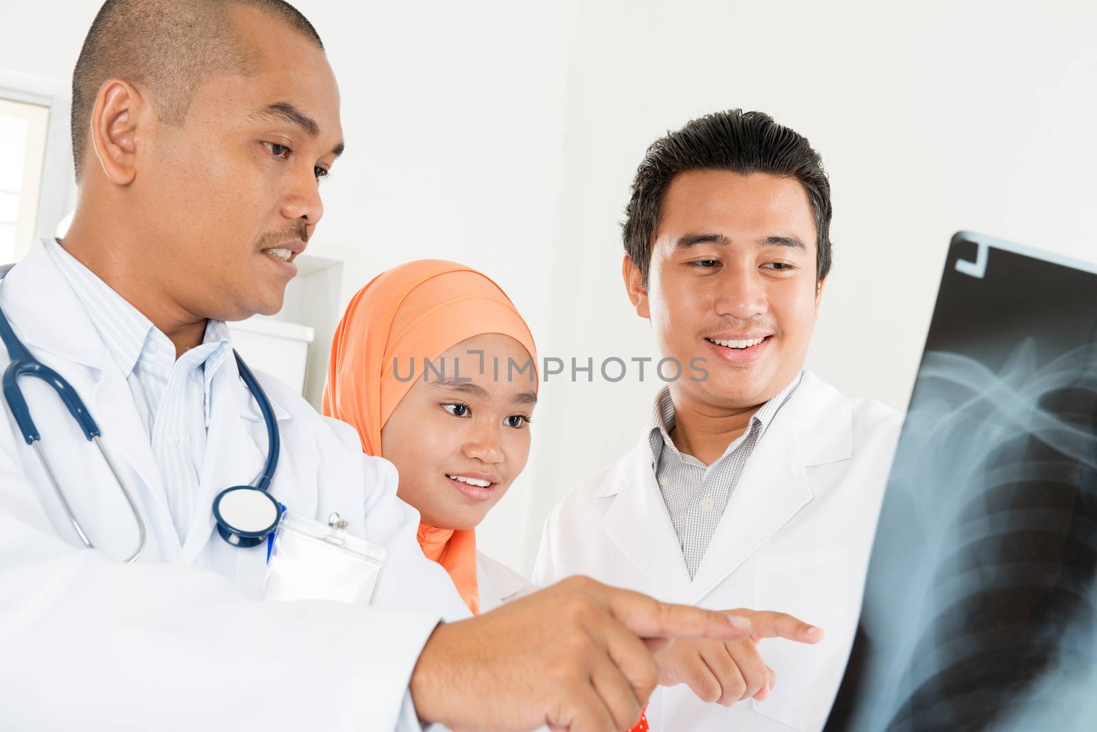 Doctors examining radiography in office. Southeast Asian Muslim people.