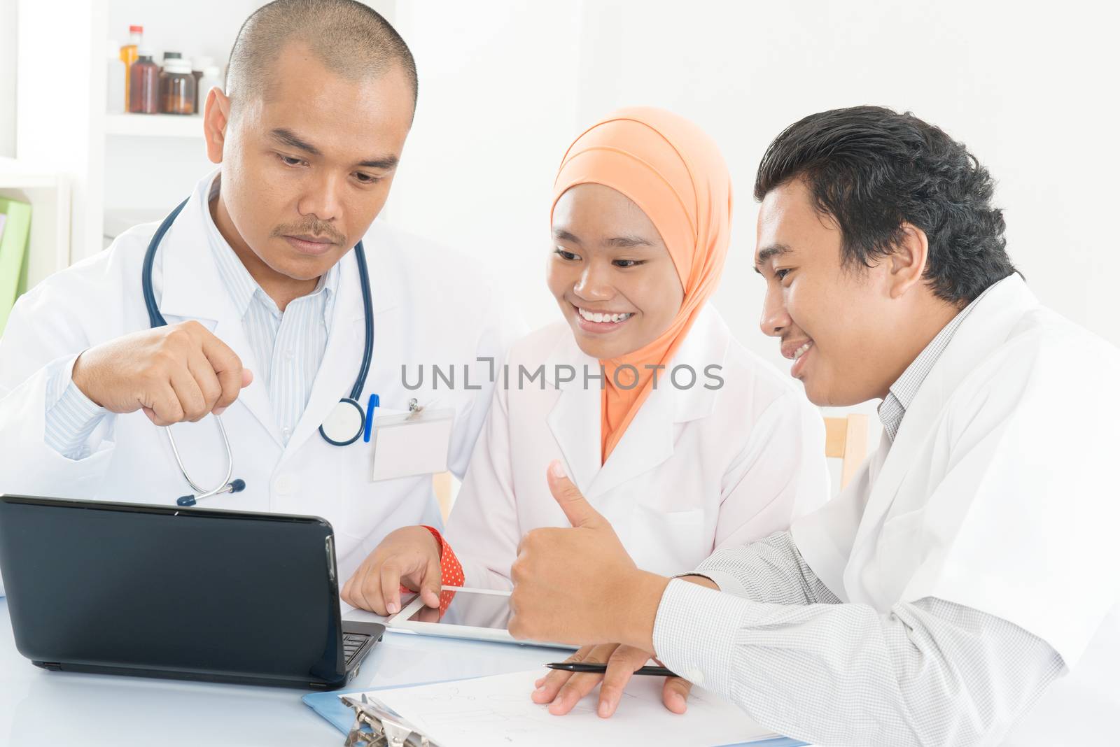 Group of doctors discuss at meeting in hospital office and showing thumb up. Southeast Asian Muslim medical people.