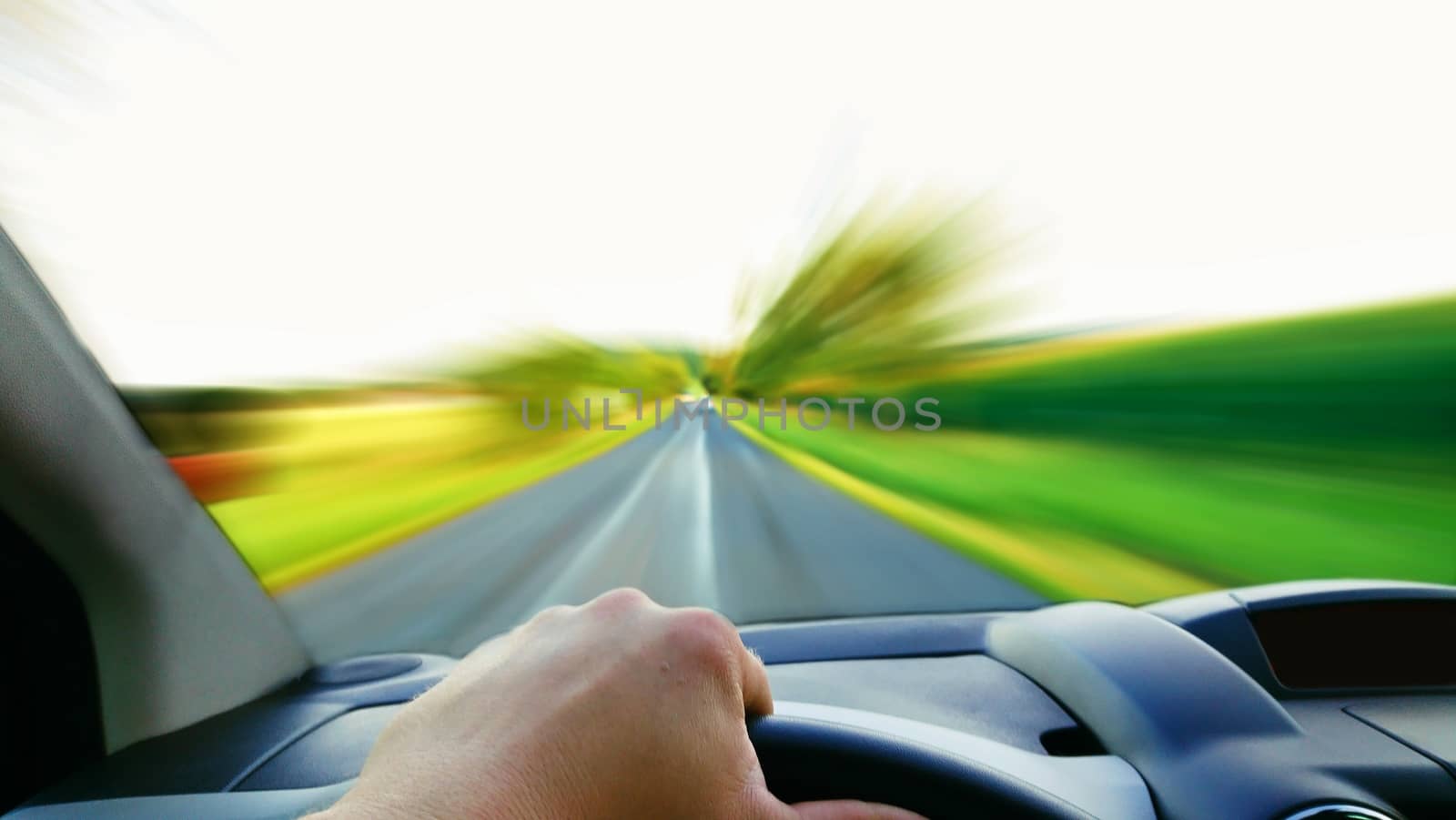 First person view of the driver behind the wheel. Driving a fast car with high speed blurred front road.