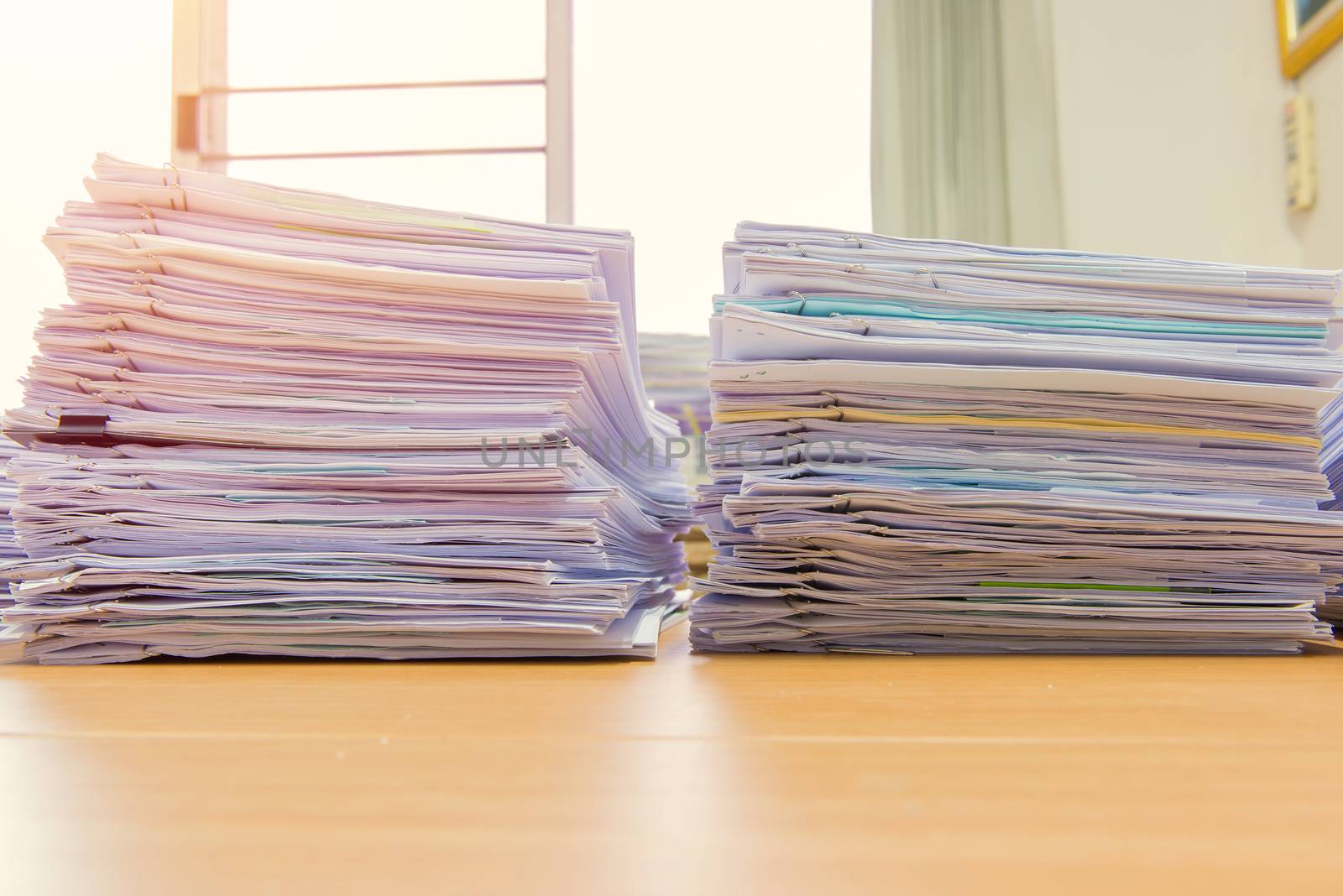 documents on desk stack up high waiting to be managed.