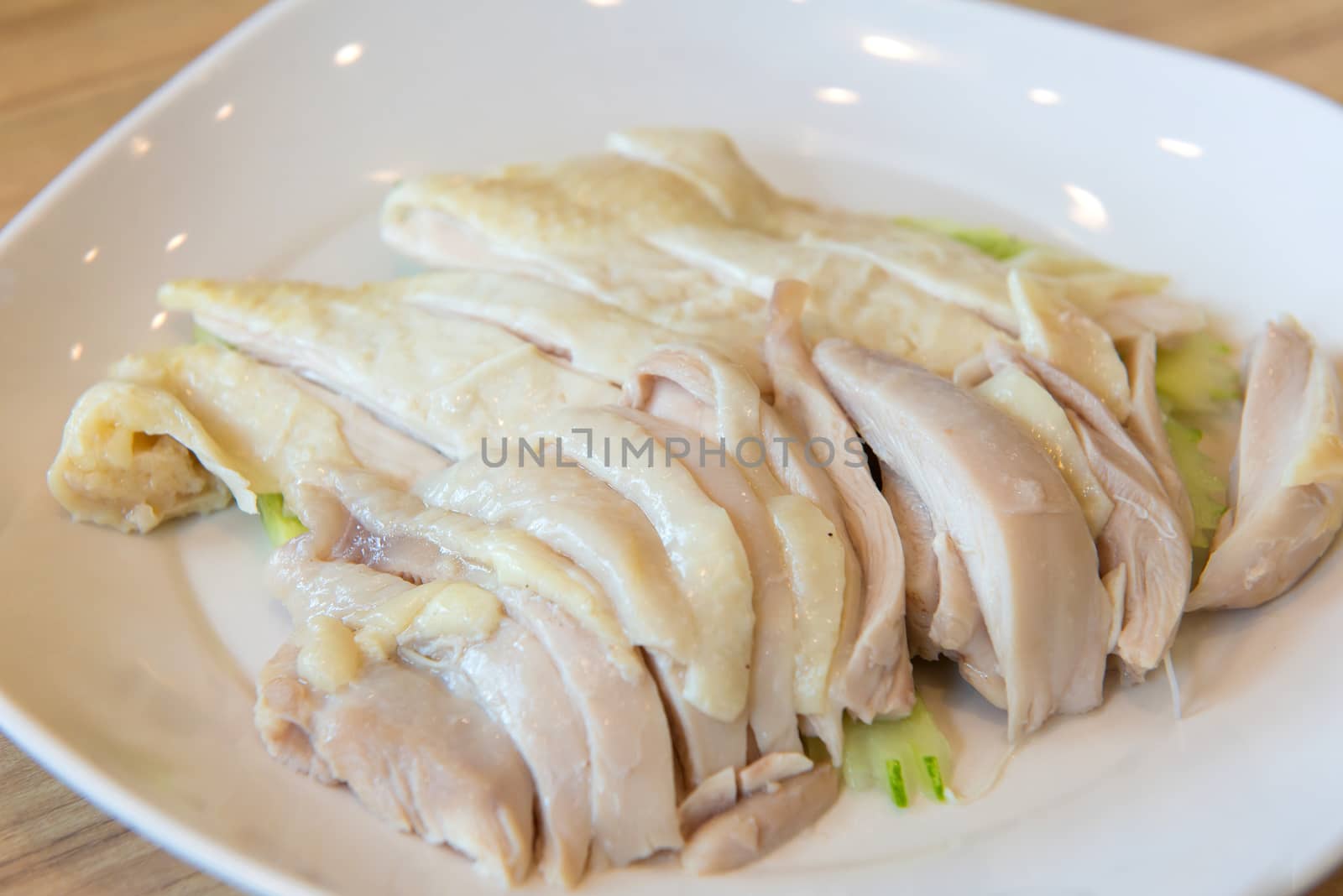 hainanese boiled chicken on white dish in restaurant.