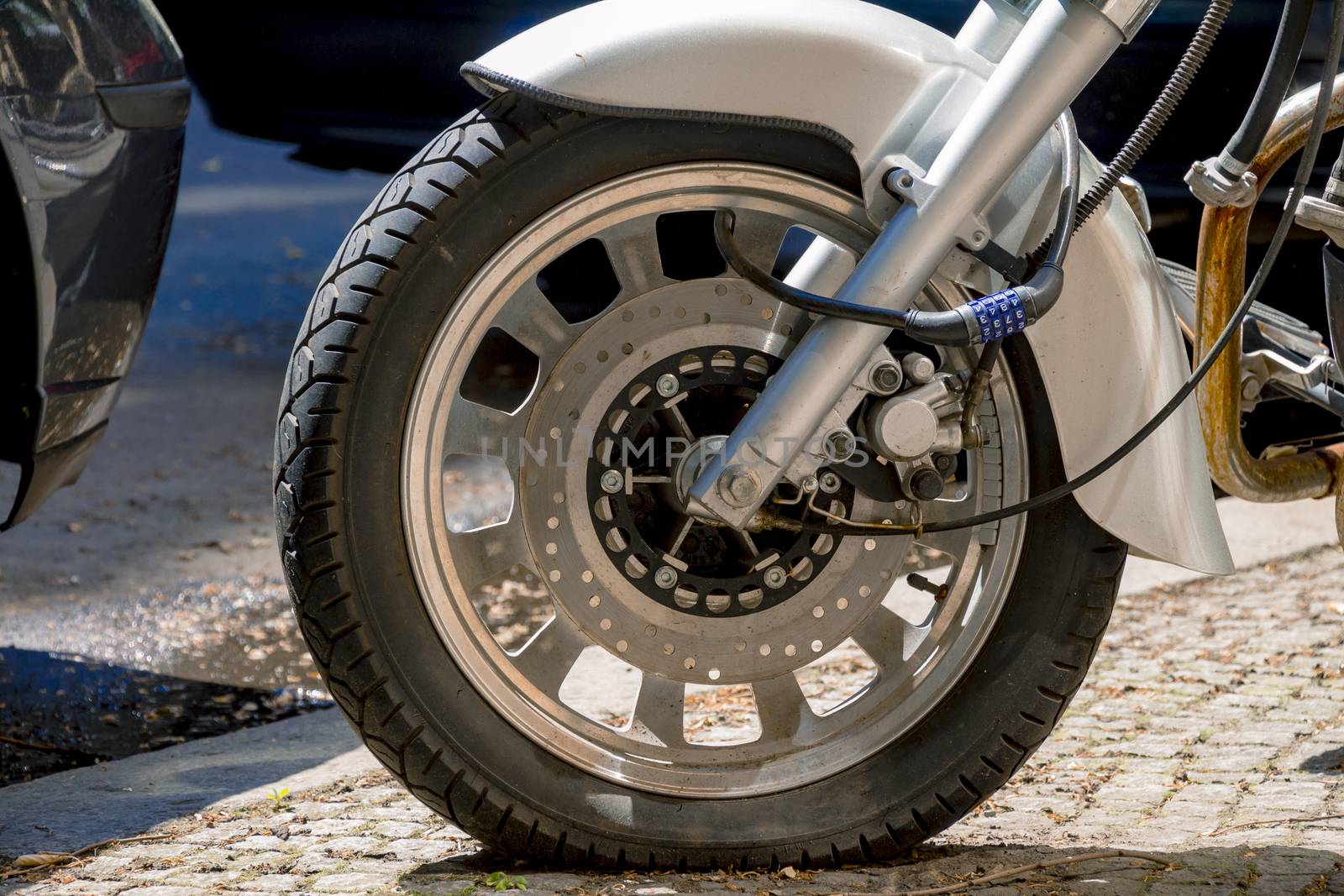 Security number padlock blocking motorcycle wheel on the street.