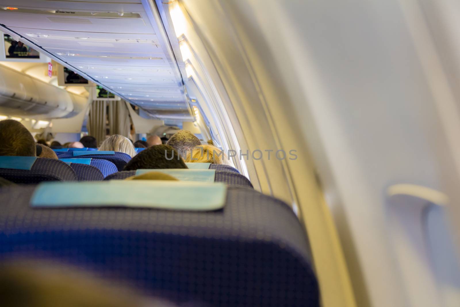 Interior of passenger airplane with people on seats.