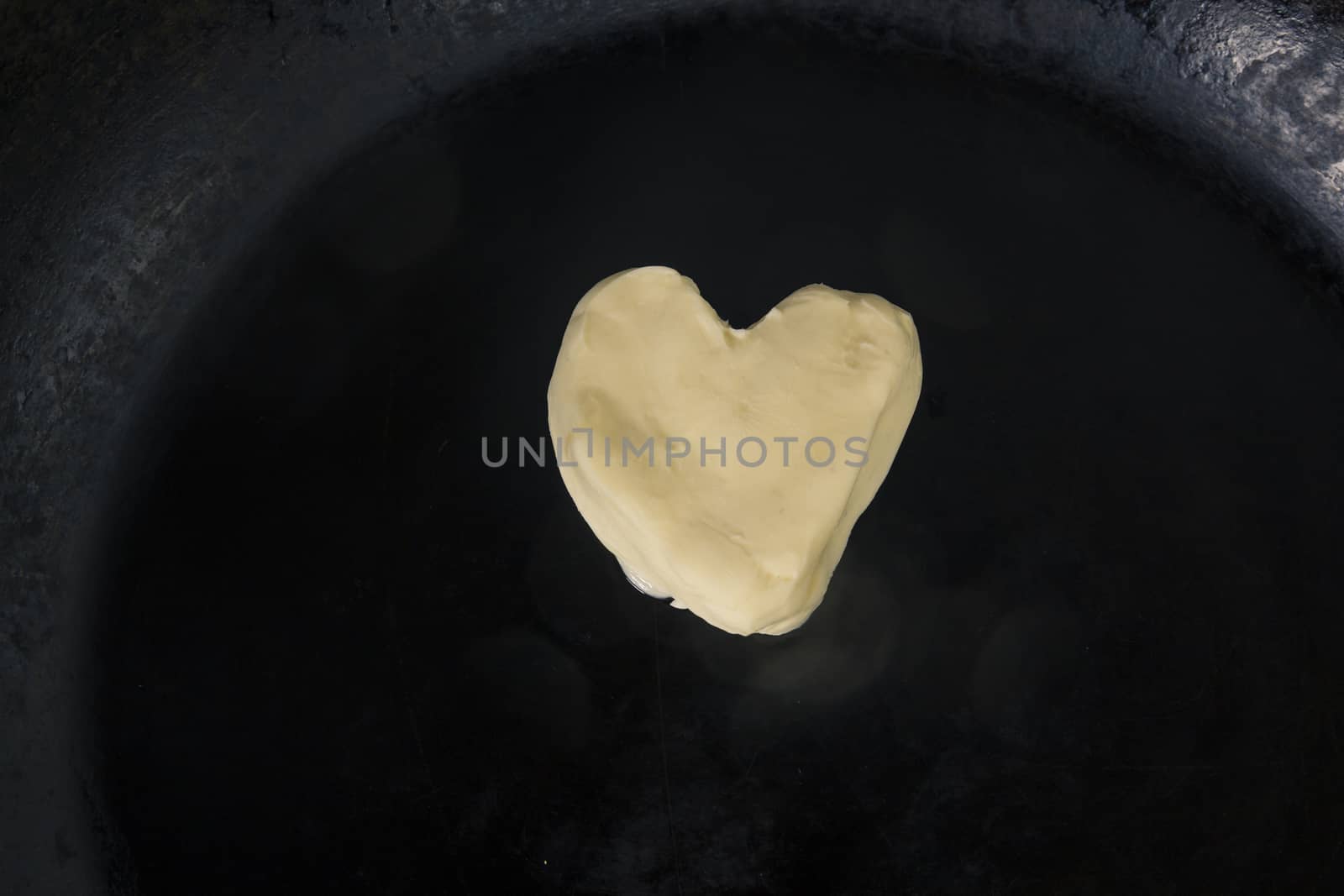 Butter in shape of heart on hot pan - Close up top view 