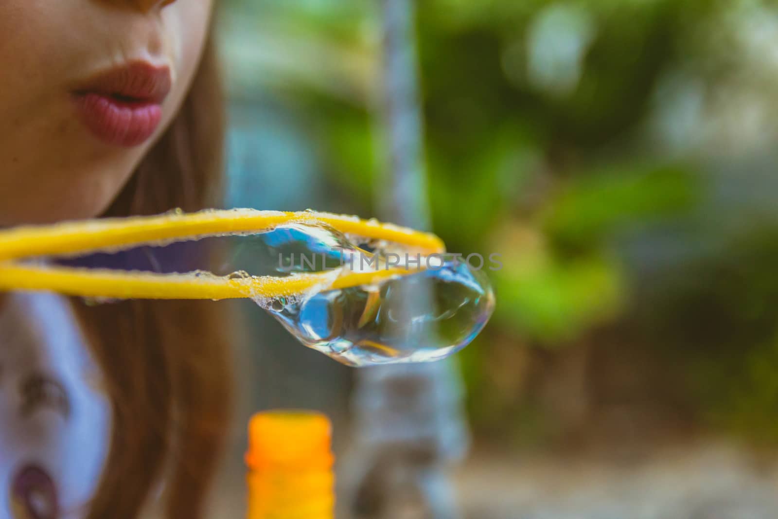 Close up of little girl blowing soap bubbles.