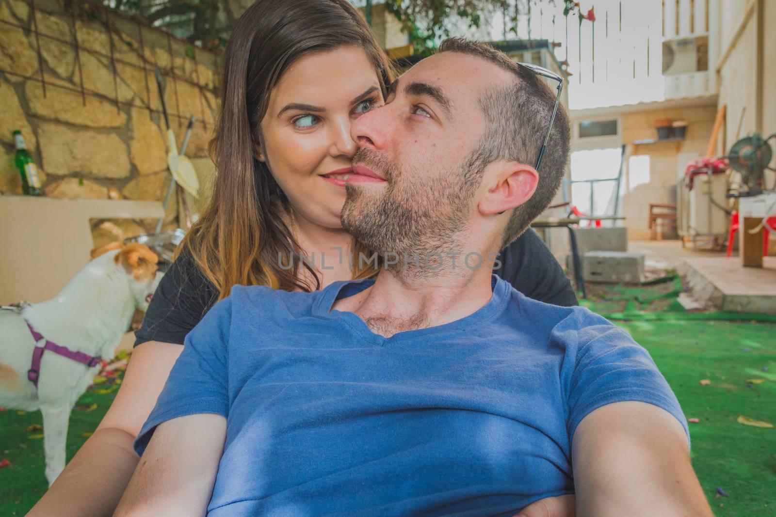 Young couple enjoying together in the backyard. They are smiling, laughing and making funny faces together.