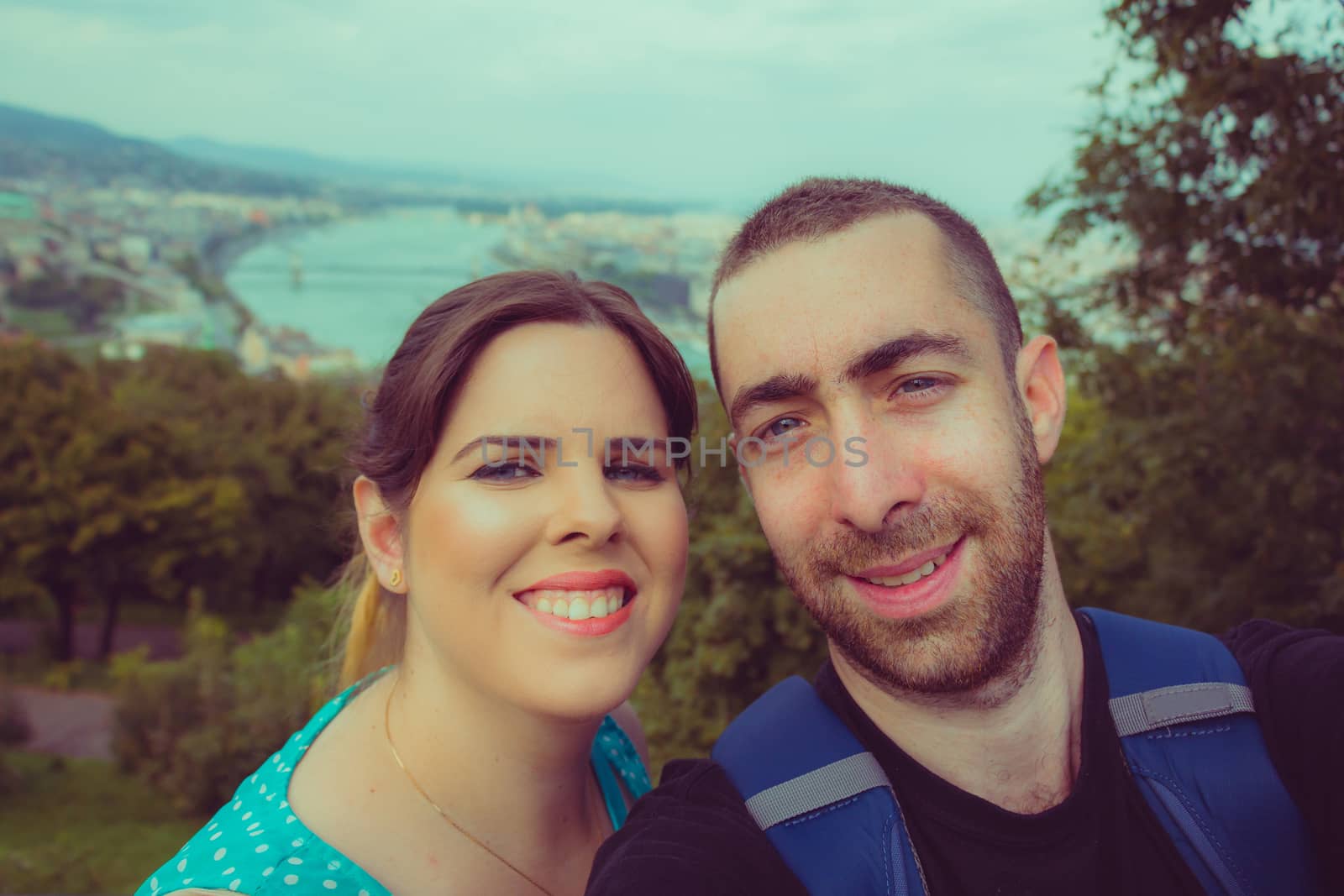 Happy couple taking selfie with smartphone or camera over Budapest cityscape background.