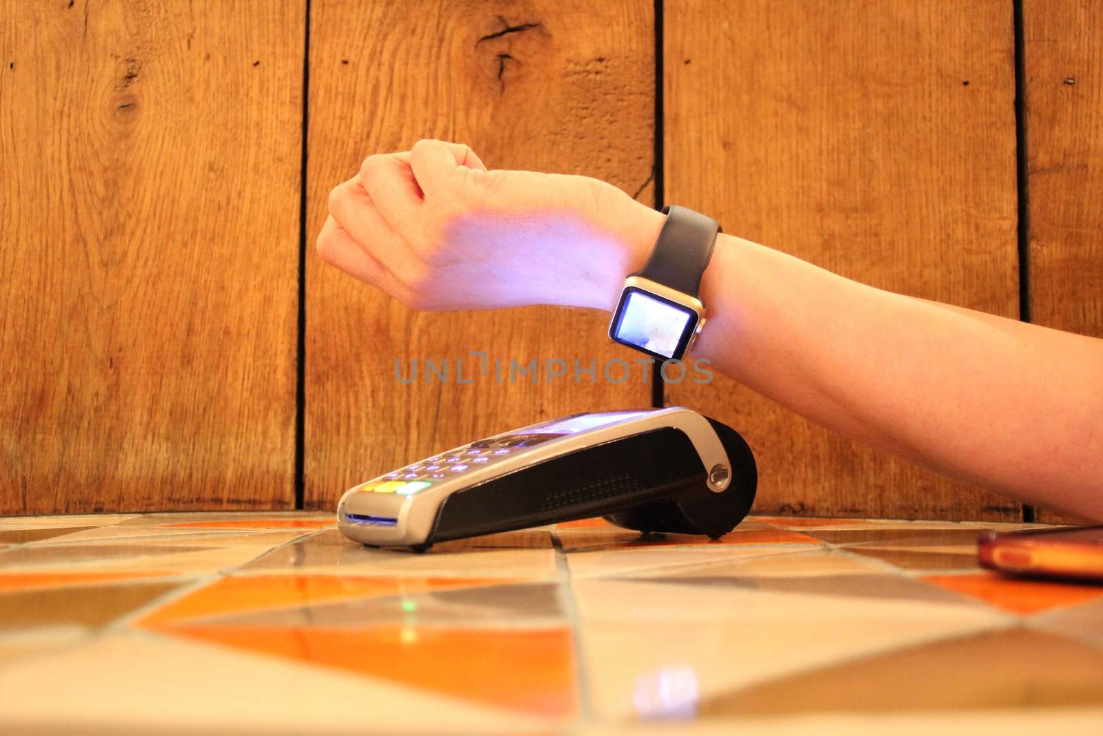 contactless payment apple watch pdq with hand holding credit card to pay by cheekylorns