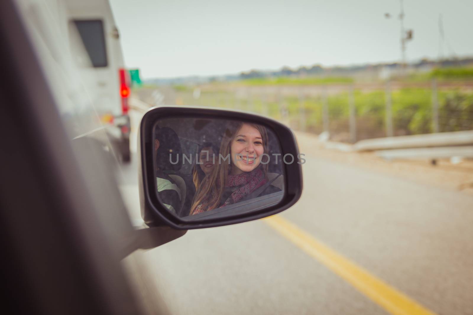 Women looking at the camera through the car side view mirror .