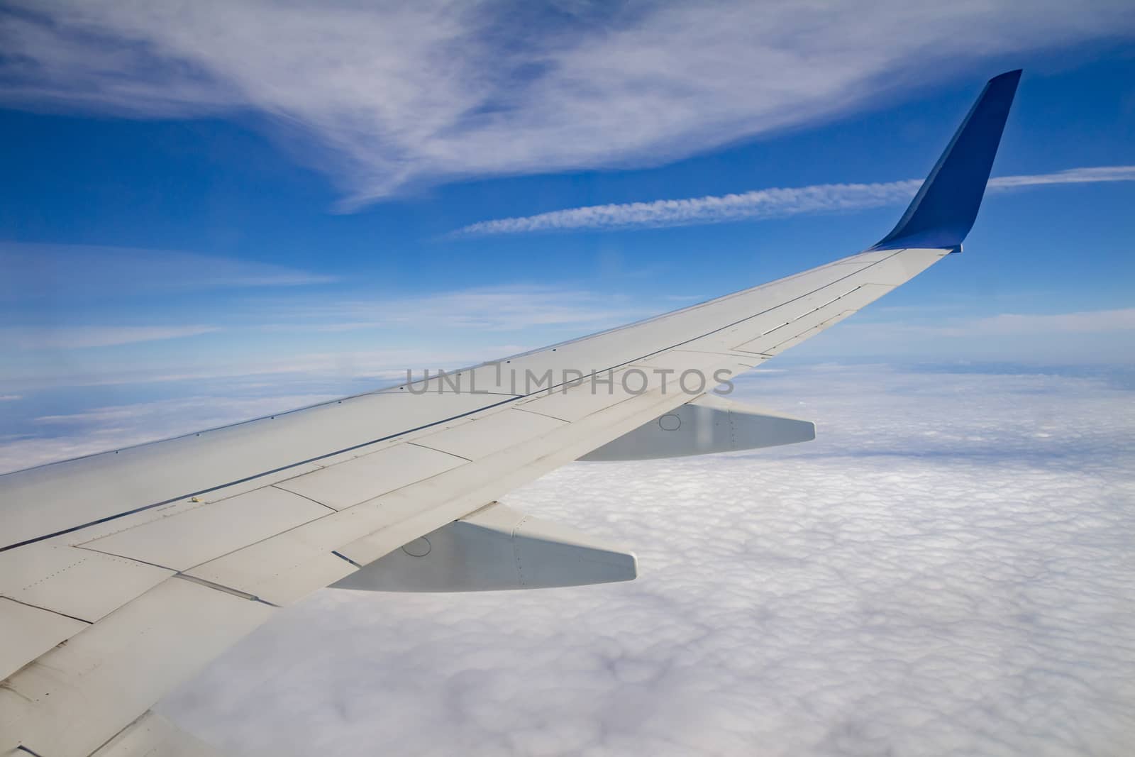 Airplane wing on the sky and over sea with clouds.