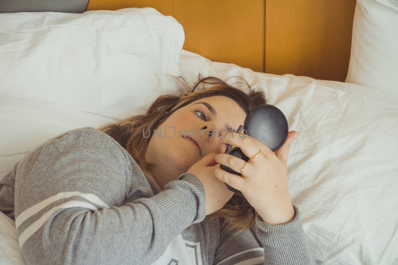 Woman applying makeup while she is lying on her bed