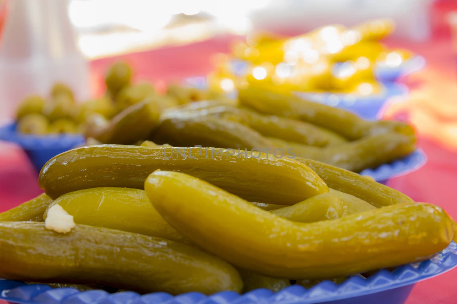 Appetizer food with pickled vegetables of cucumber and olives on picnic table.
