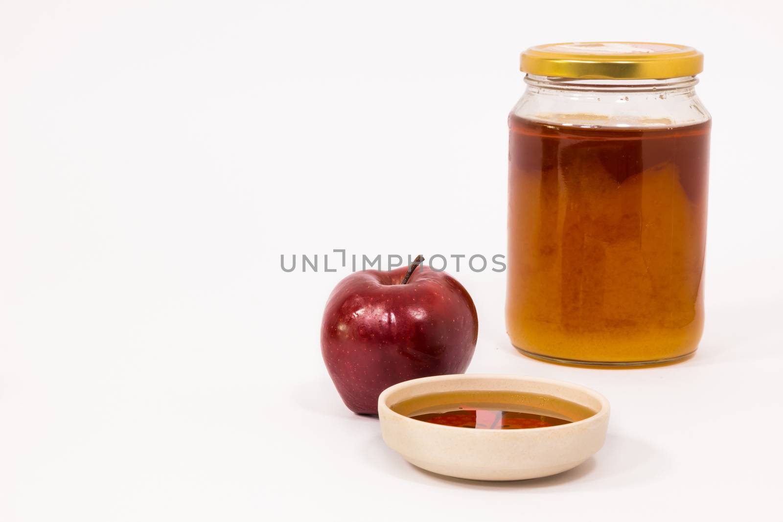 Red apple and jar of honey bowl of honey isolated on a white background. Symbols of Jewish New Year - Rosh Hashanah.