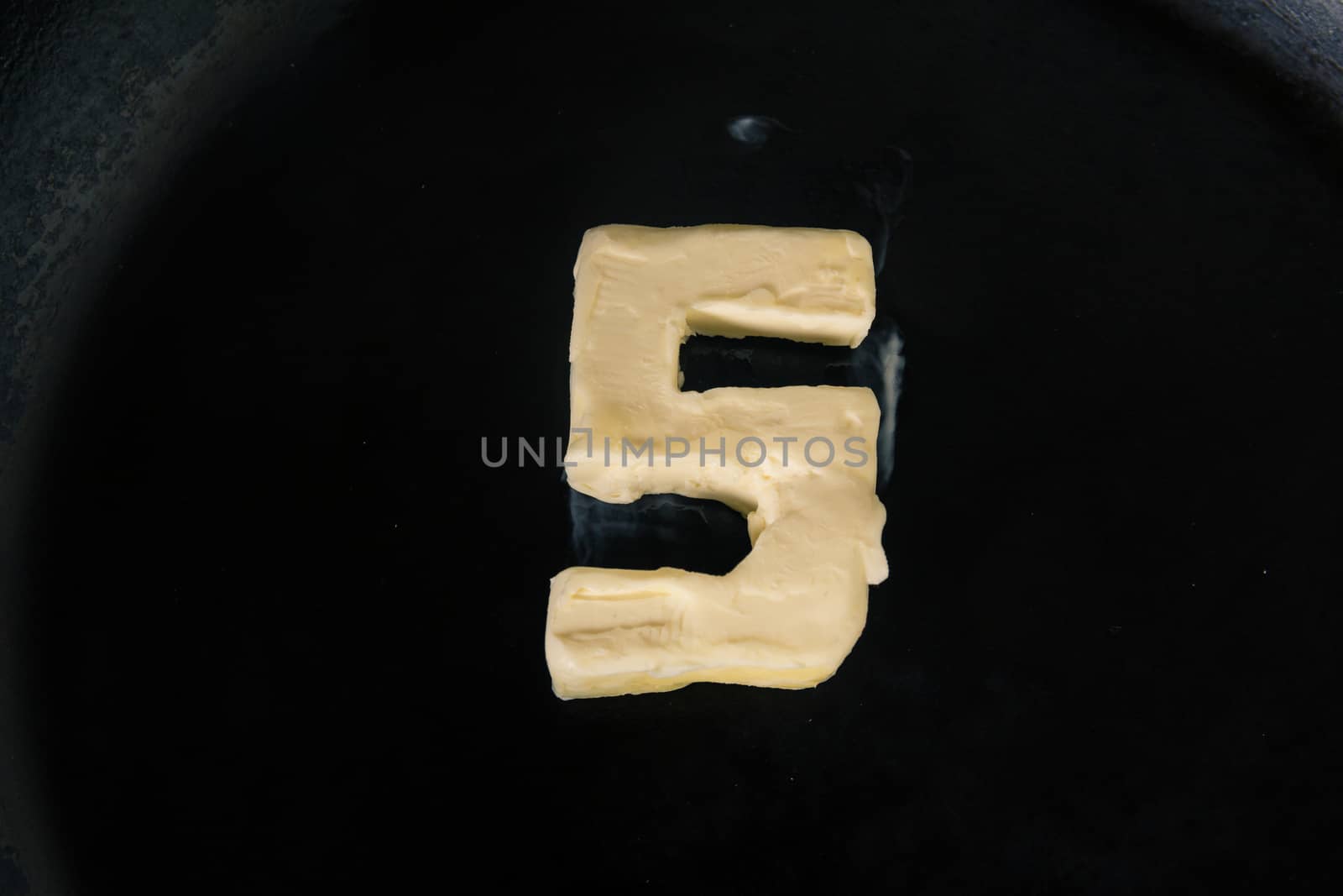 Butter in shape of number 5 on hot pan - Close up top view.