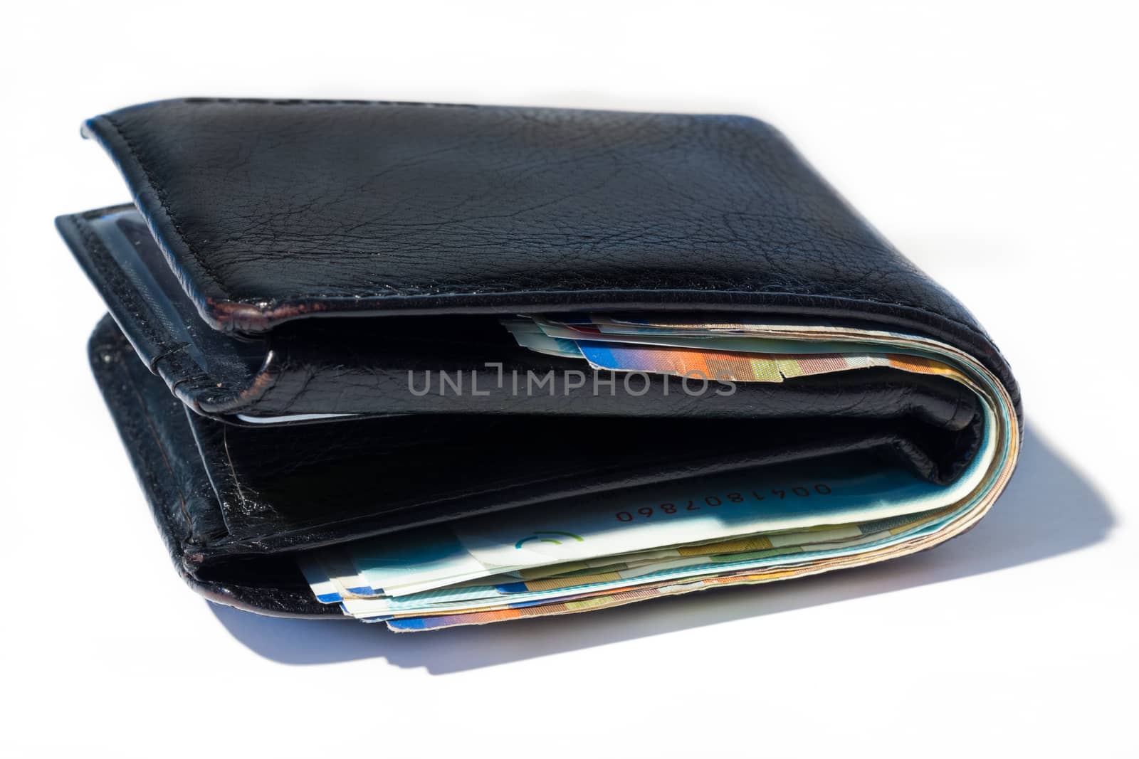 Stack of various of israeli shekel money bills in close black leather wallet.