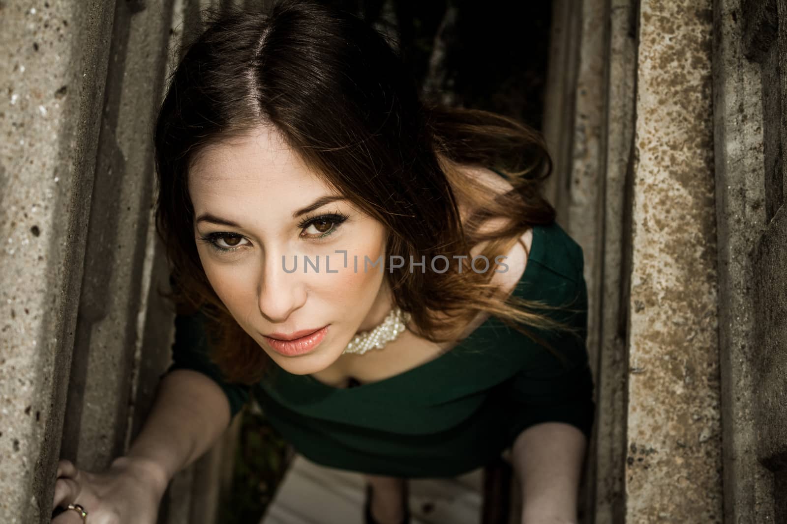 Beautiful brunette woman posing outdoor in abandoned industrial place - dark mysterious artistic portrait.