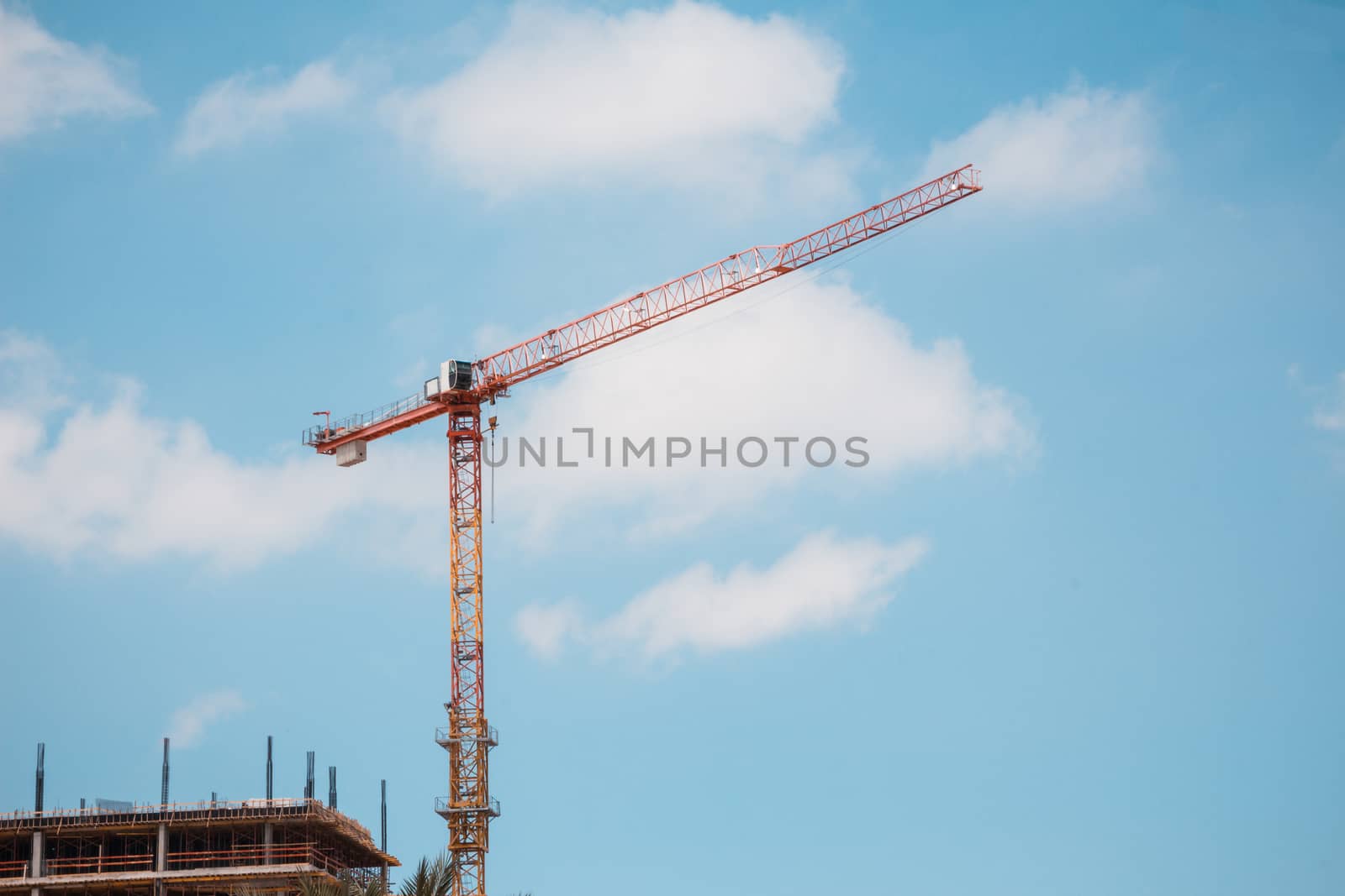 Tower crane in construction site over blue sky with clouds .