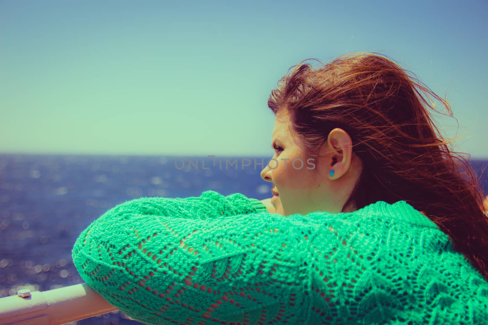 Woman leans on the railing and looking out to sea on the horizon