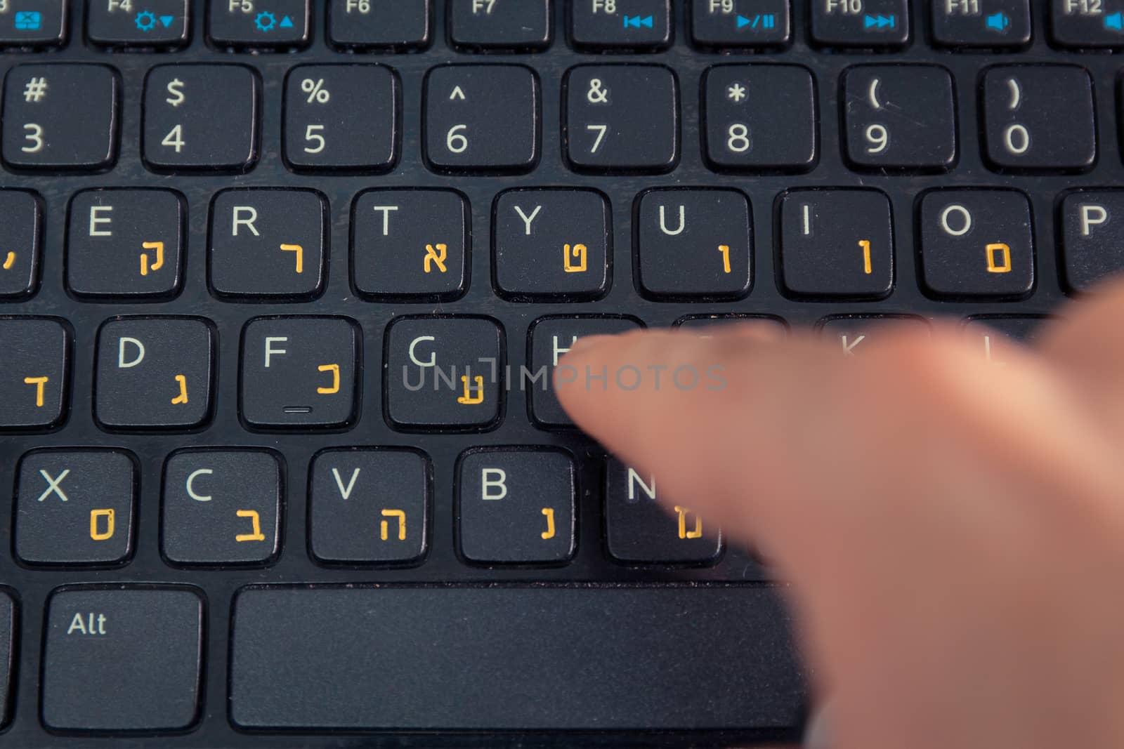 Man typing on a keyboard with letters in Hebrew and English - Laptop keyboard - Top View - Close up