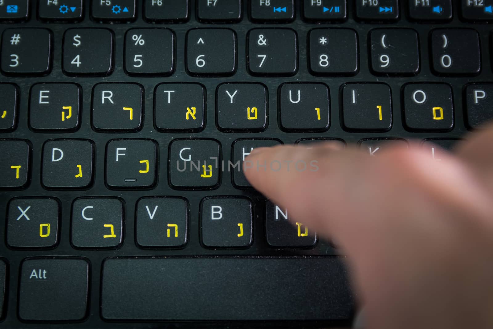 Man typing on a keyboard with letters in Hebrew and English - Laptop keyboard - Top View - Close up_Dark atmosphere