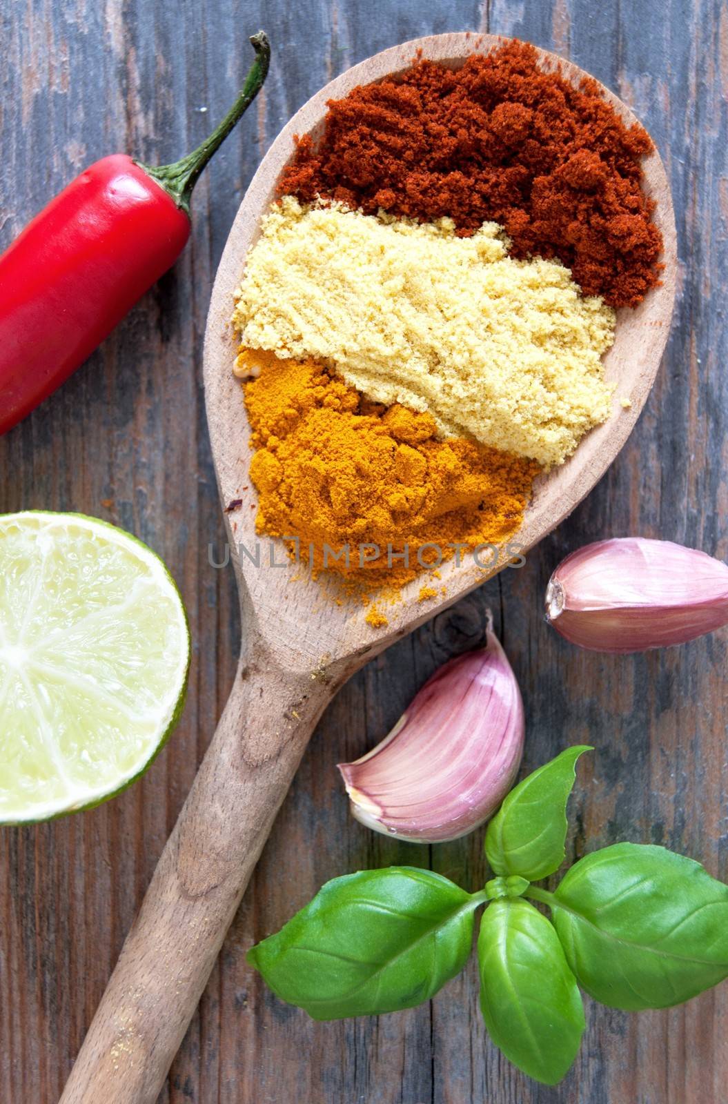 Mix of herbs in a wooden spoon with seasoning ingredients on the side