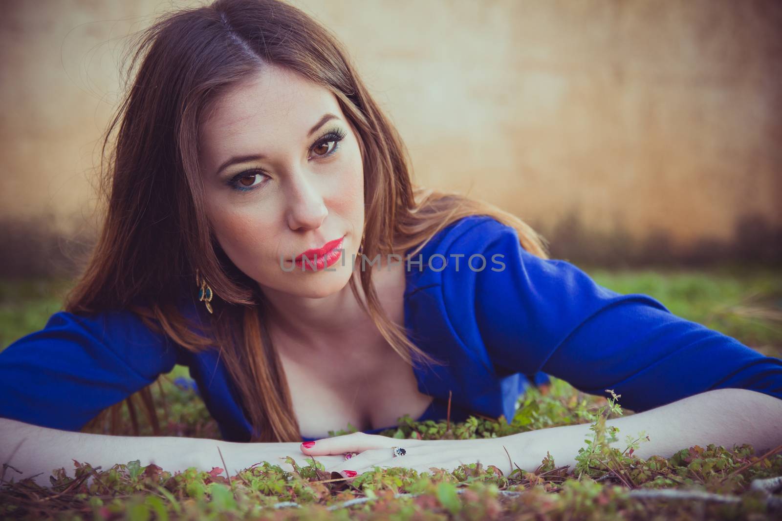 Beautiful brunette woman lying on the grass and looking at the camera.