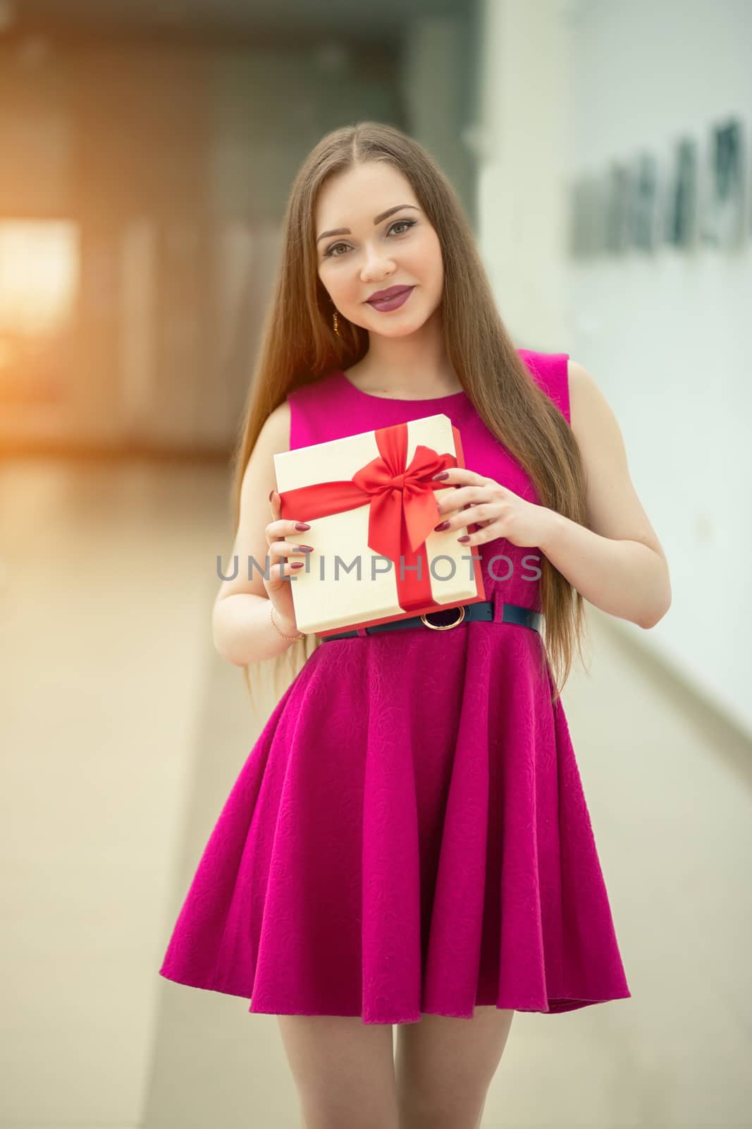 Beautiful smiling woman with long hair holding gift box