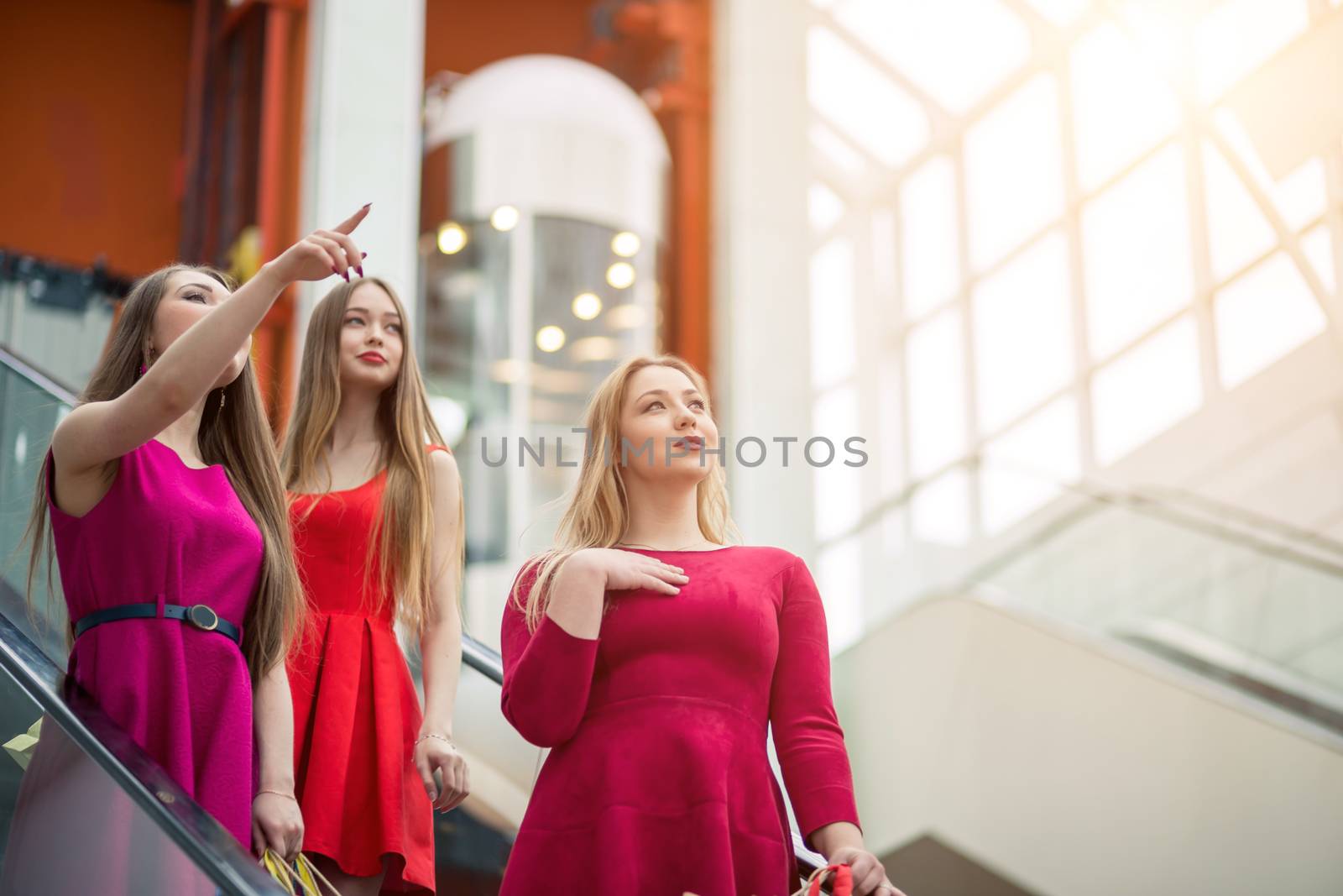 three girlfriends on escalator with shopping bags