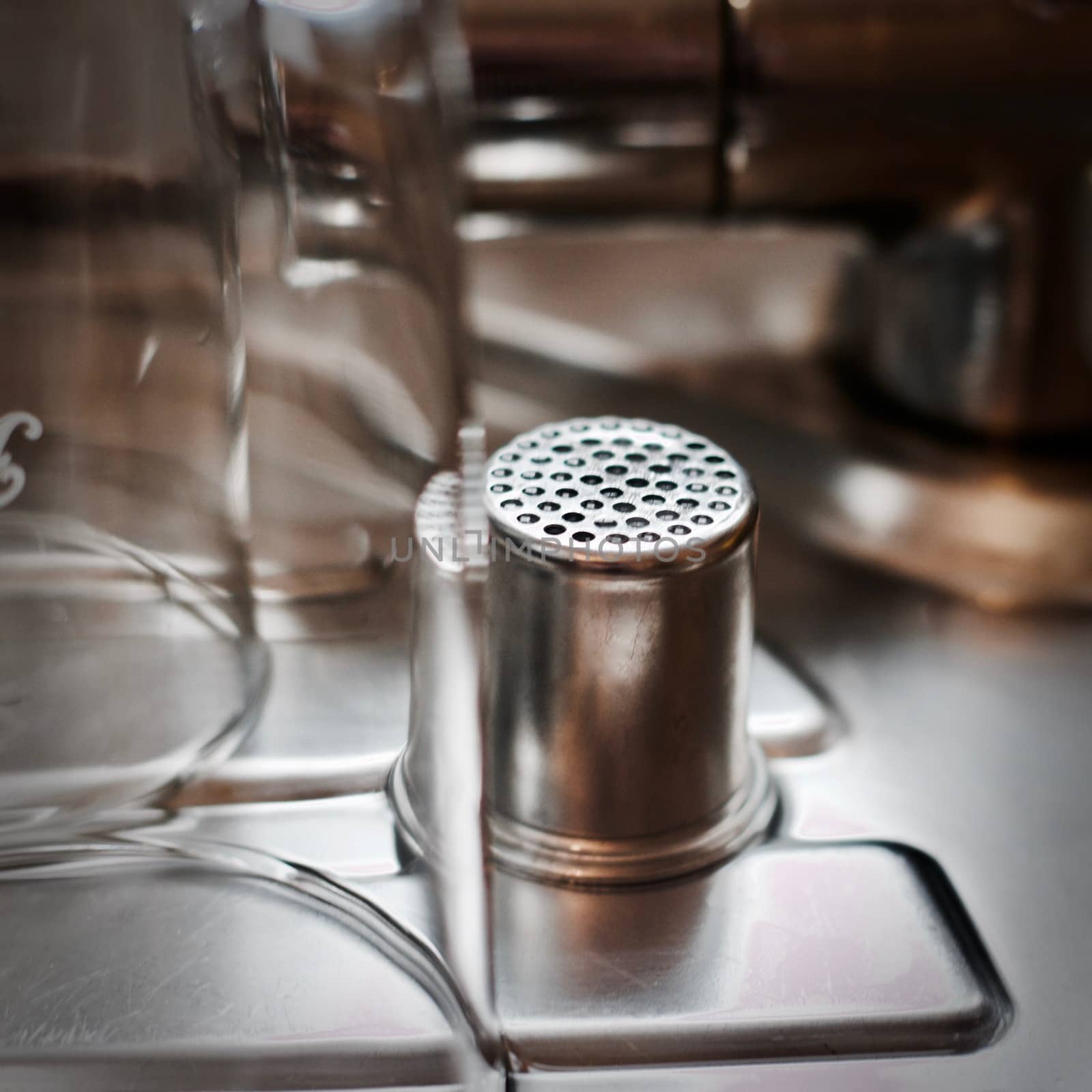 Kitchen stuff concept. Silver garlic strainer near glasses drying.