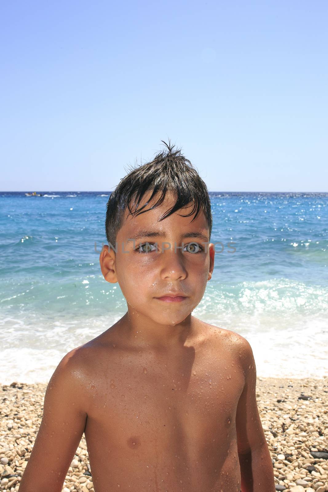 Boy with beautiful green eyes on the beach