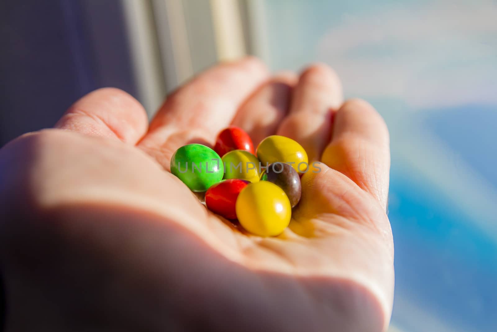 Man hand holding colorful chocolate candies buttons.