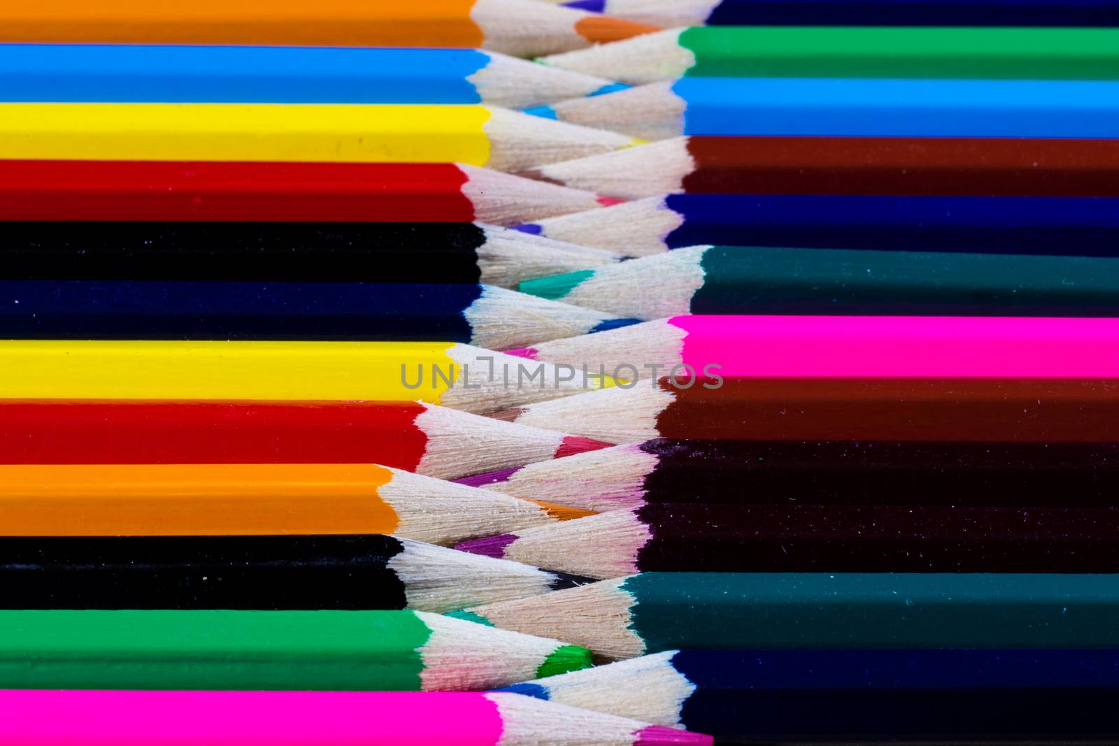 Beautiful and colorful pencil crayons. Wooden table. Black background.