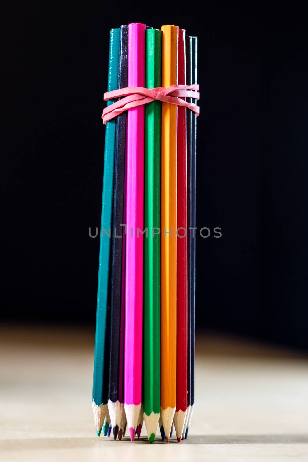 Beautiful and colorful pencil crayons. Wooden table. Black background.
