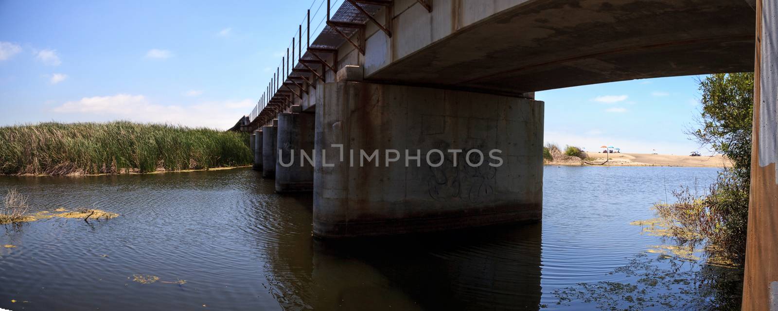 Water under the railroad track bridge leading down to the ocean by steffstarr